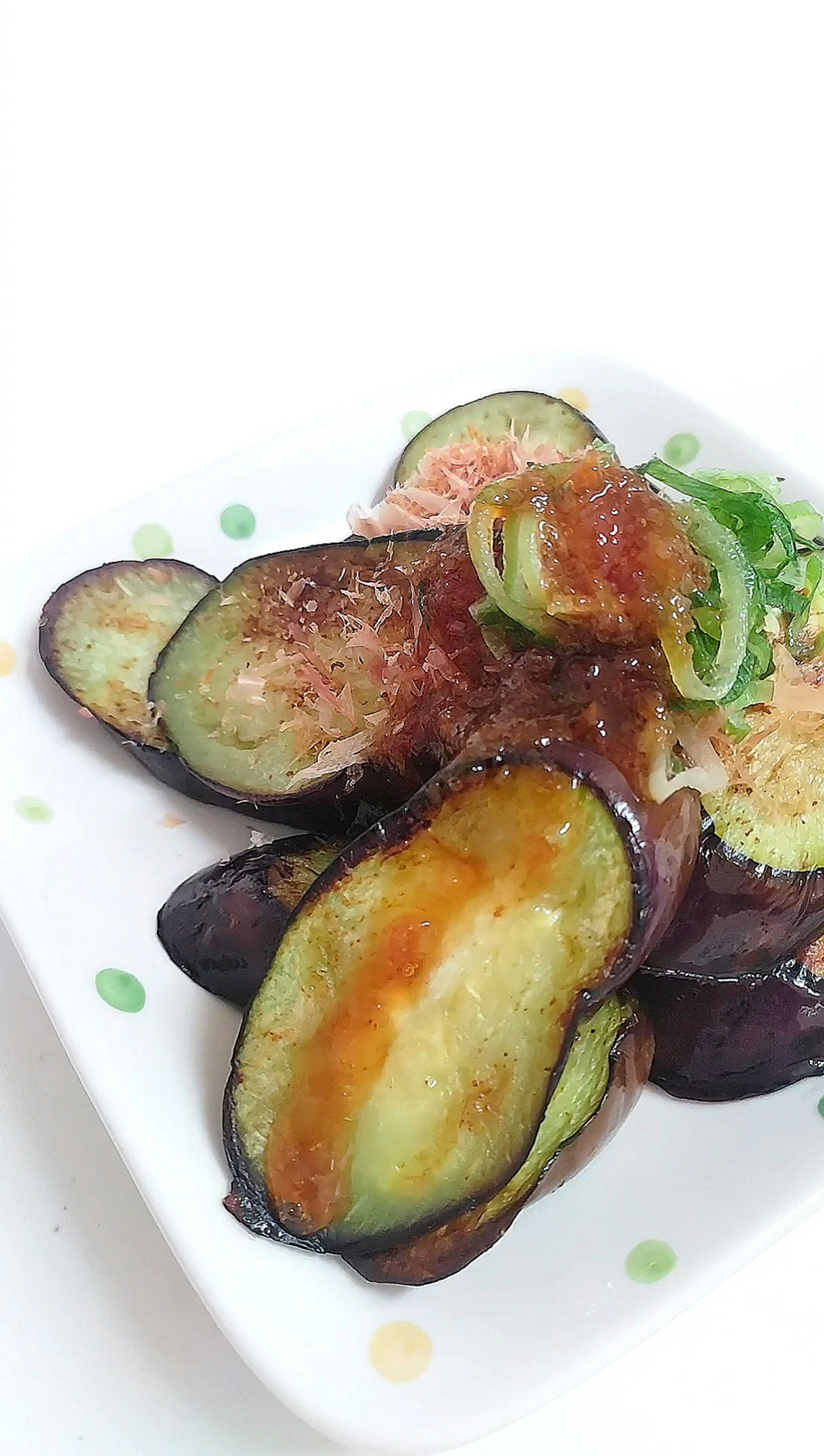 Sliced eggplant dish topped with sauce and garnished on a plate