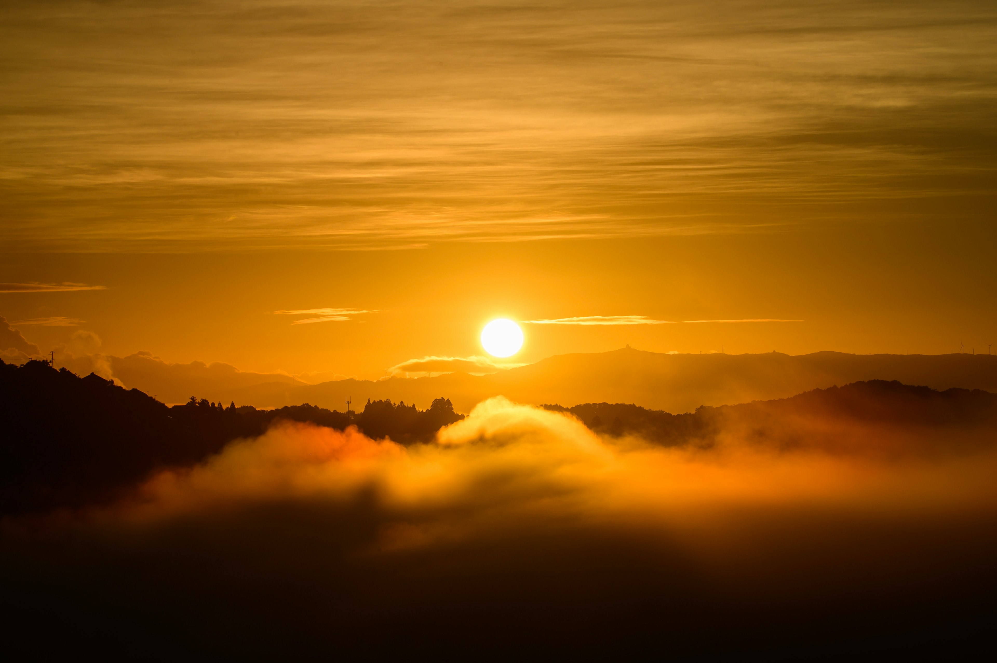 Sole arancione che sorge su montagne nebbiose con nuvole morbide