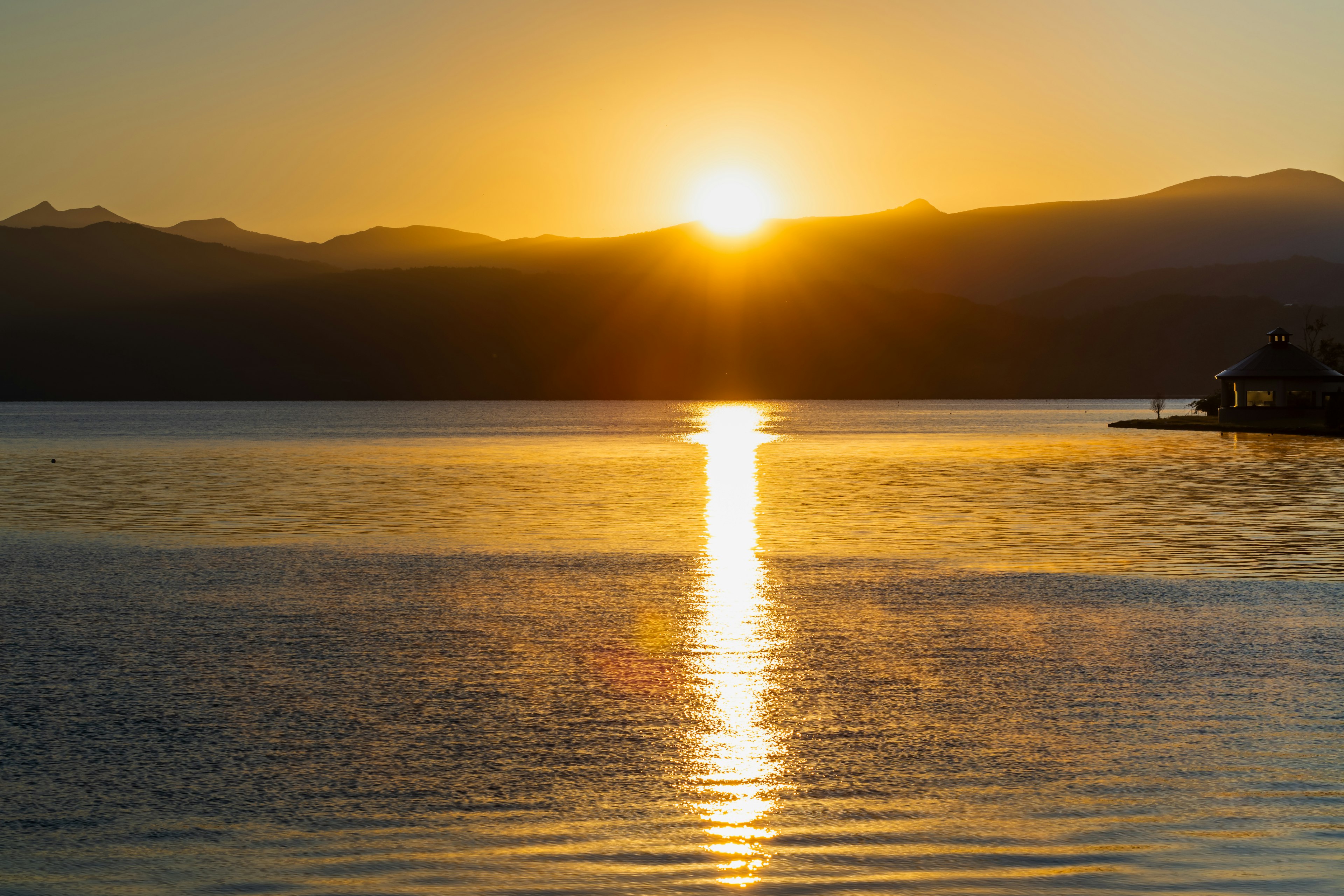 Un beau coucher de soleil se levant entre les montagnes reflété sur la surface du lac