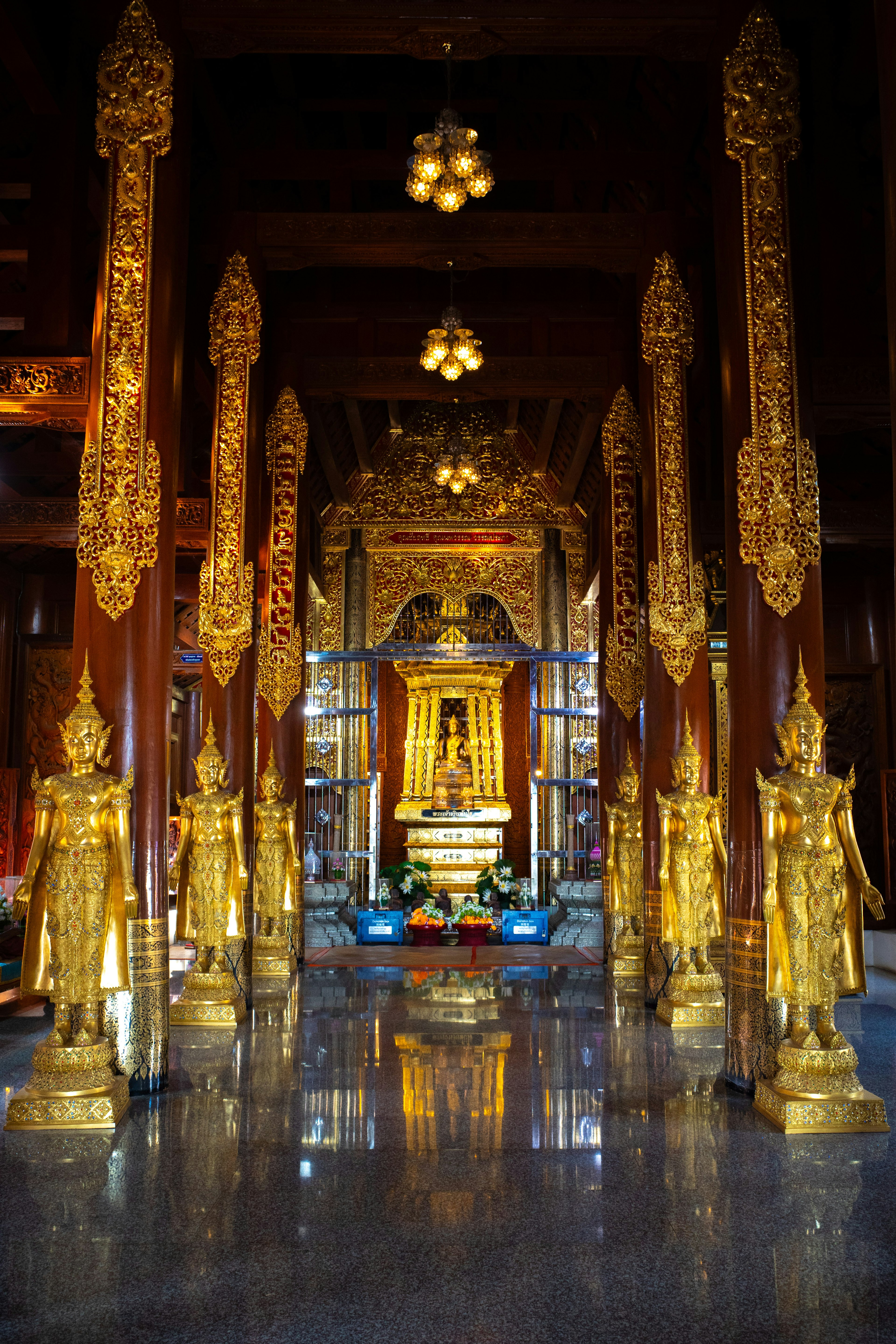 Interior of a temple featuring ornate golden statues and decorative pillars