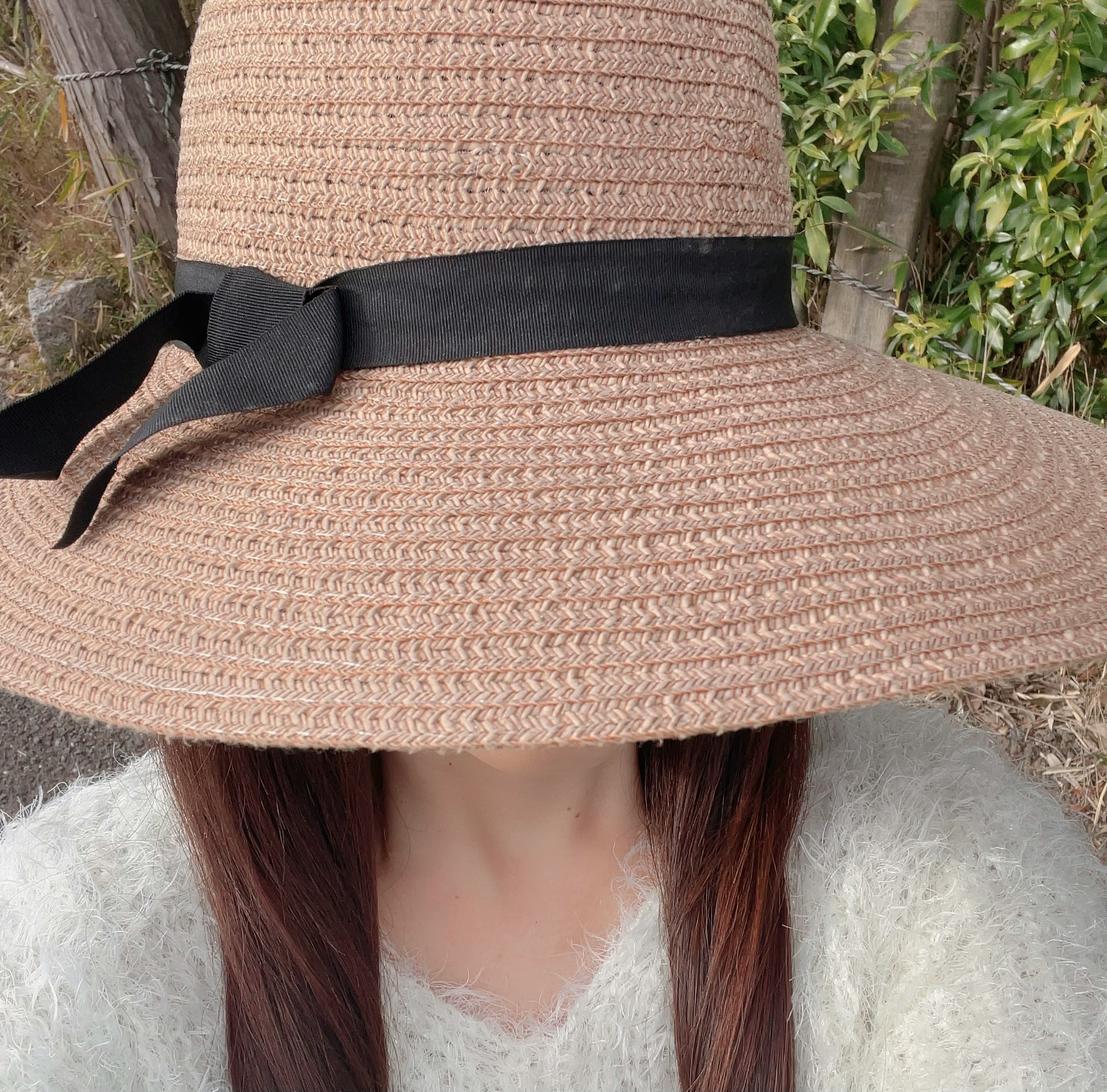 Imagen de una mujer usando un gran sombrero de paja con una cinta negra