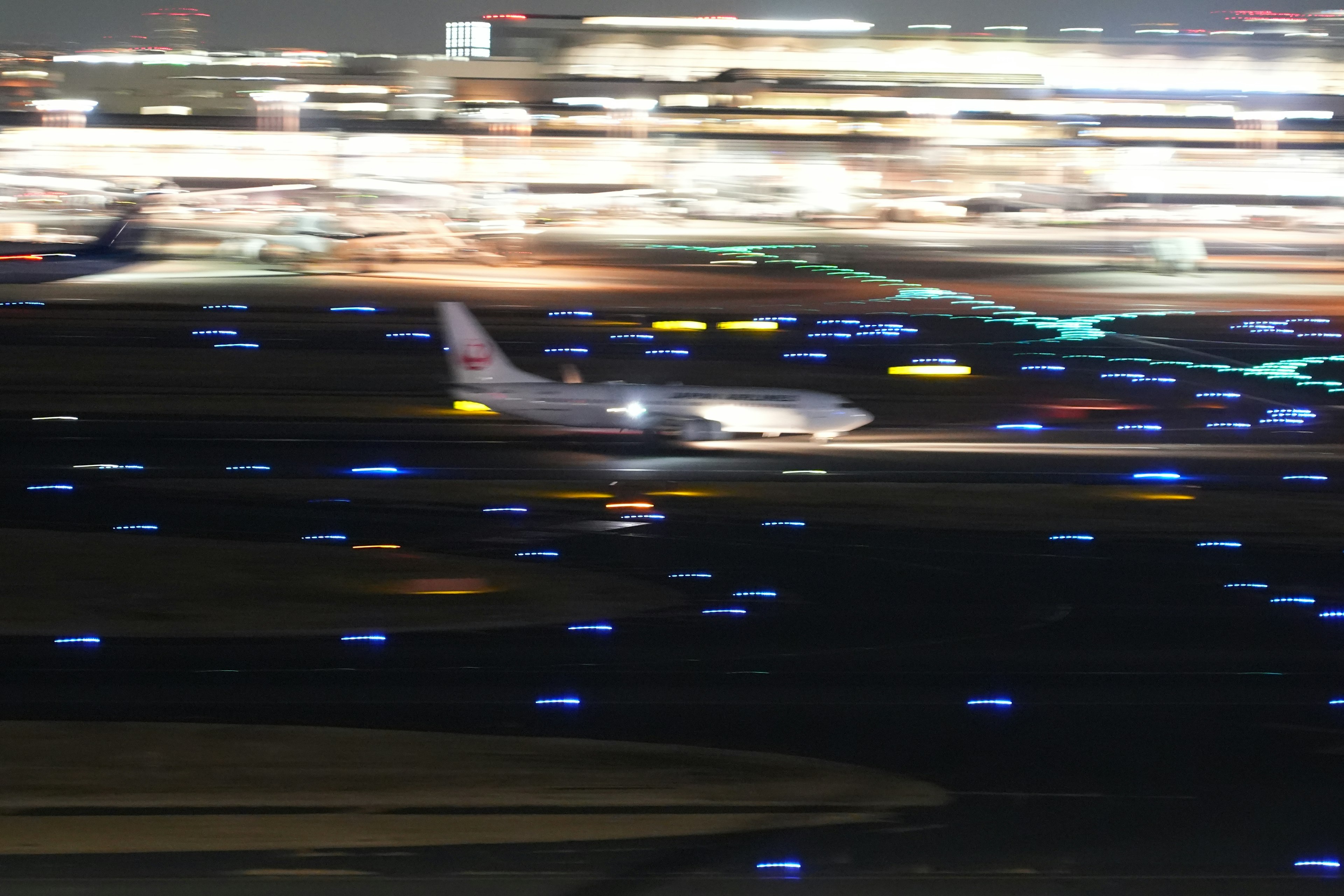 Immagine sfocata di un aereo che taxiando su una pista di notte