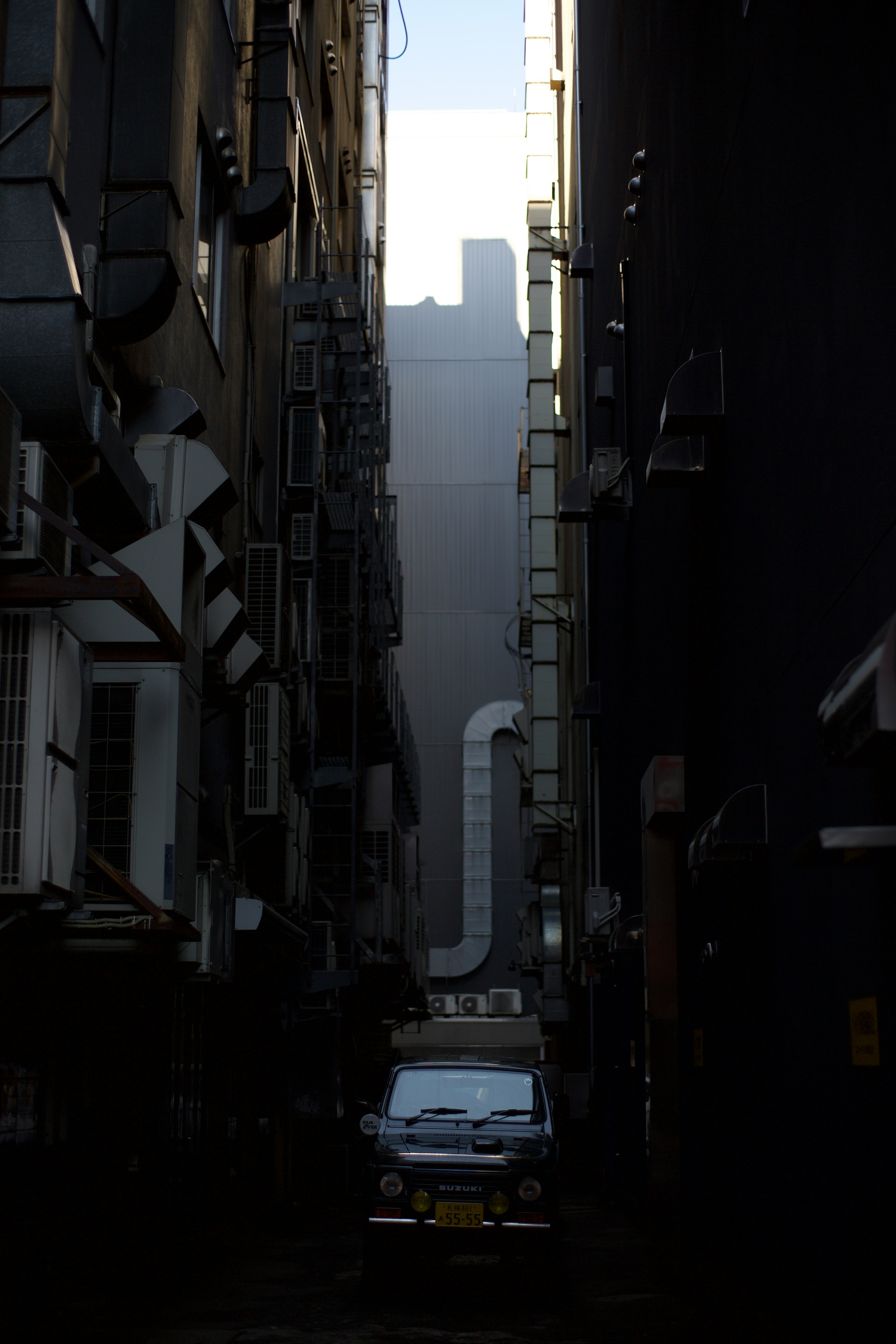 Taxi parked in a narrow alley with a silhouette of a skyscraper visible in the background