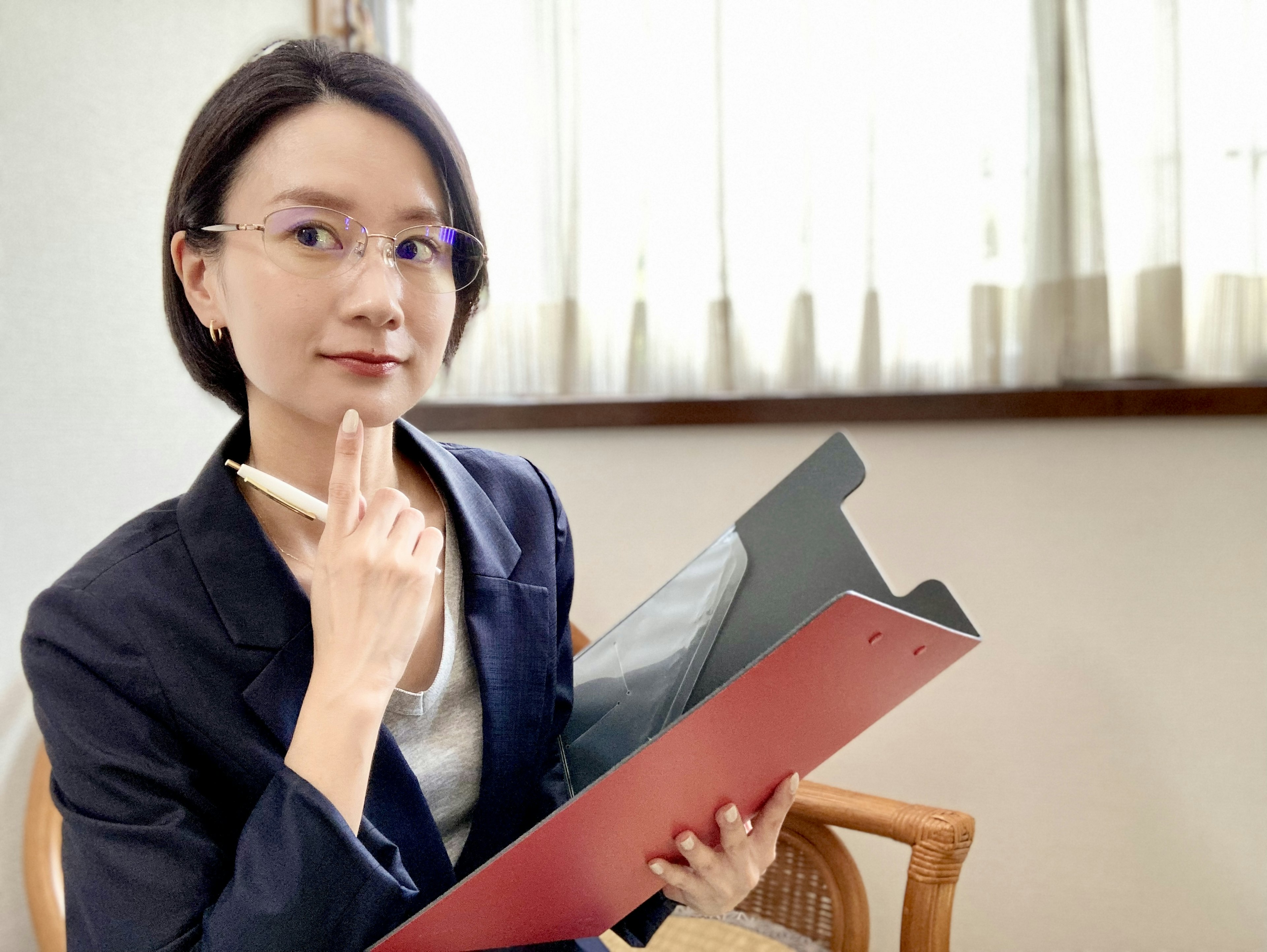 Eine junge Frau, die nachdenklich ein Clipboard und einen Stift hält