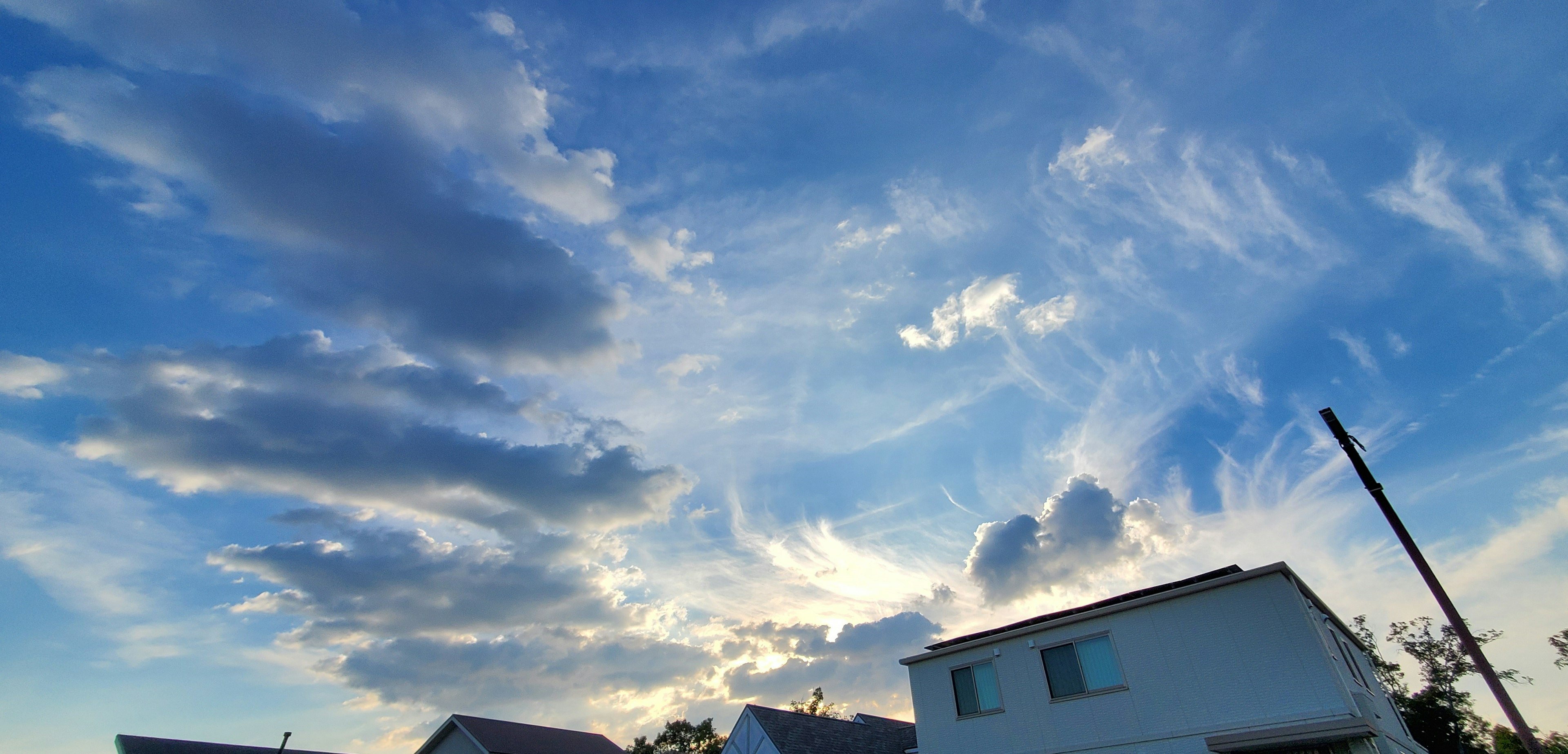 Une vue du ciel bleu avec des nuages et une maison blanche au premier plan