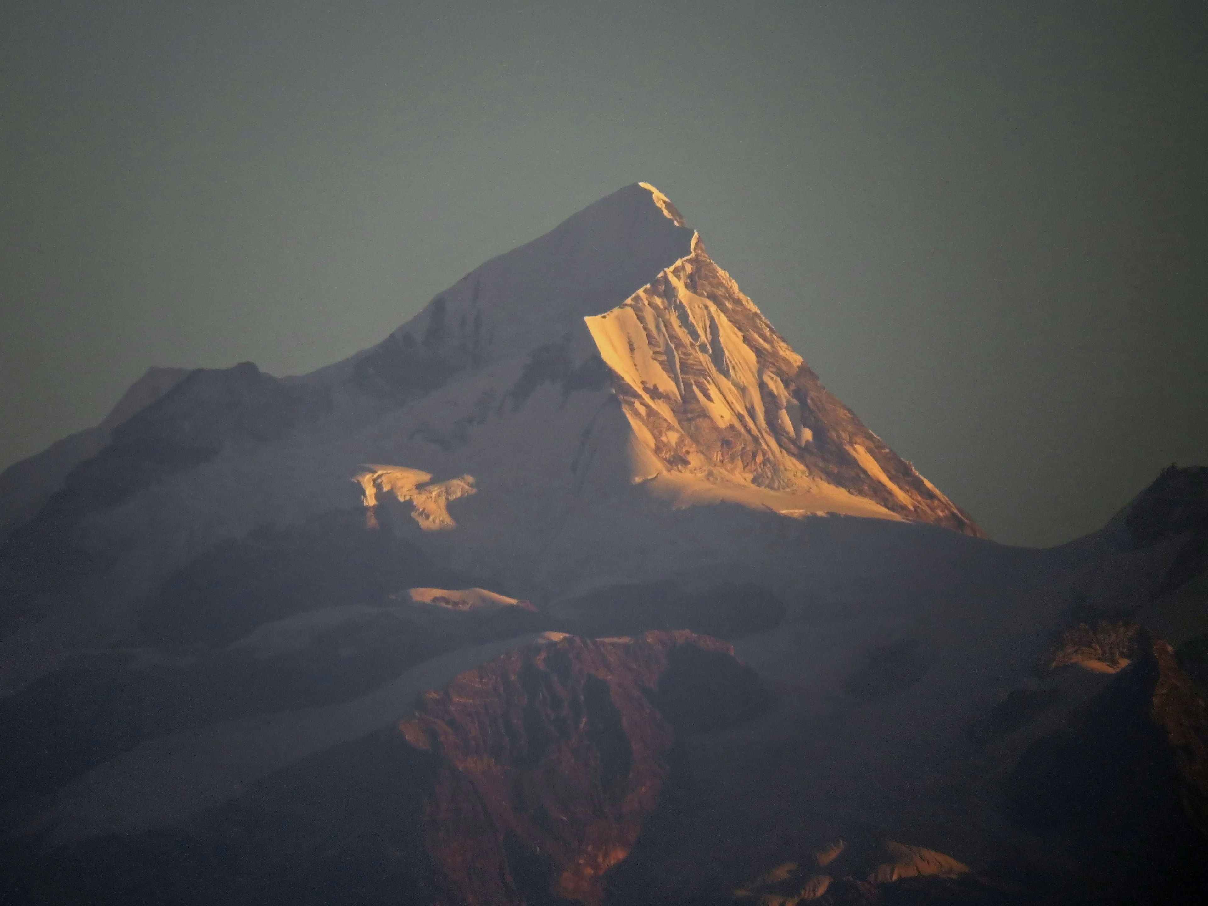 Cima de una montaña cubierta de nieve iluminada por el atardecer