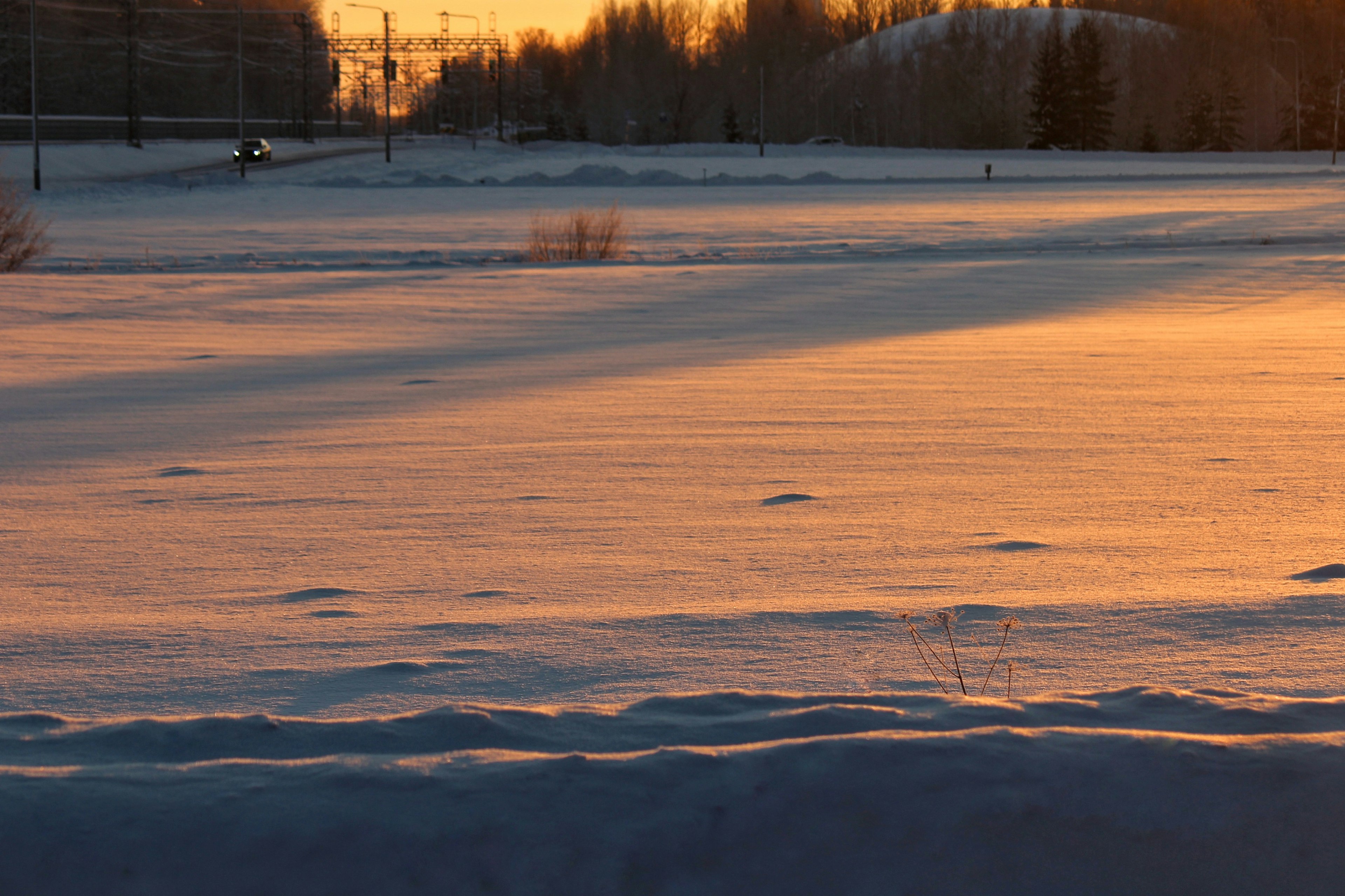 Snow-covered landscape illuminated by orange light from the sunset