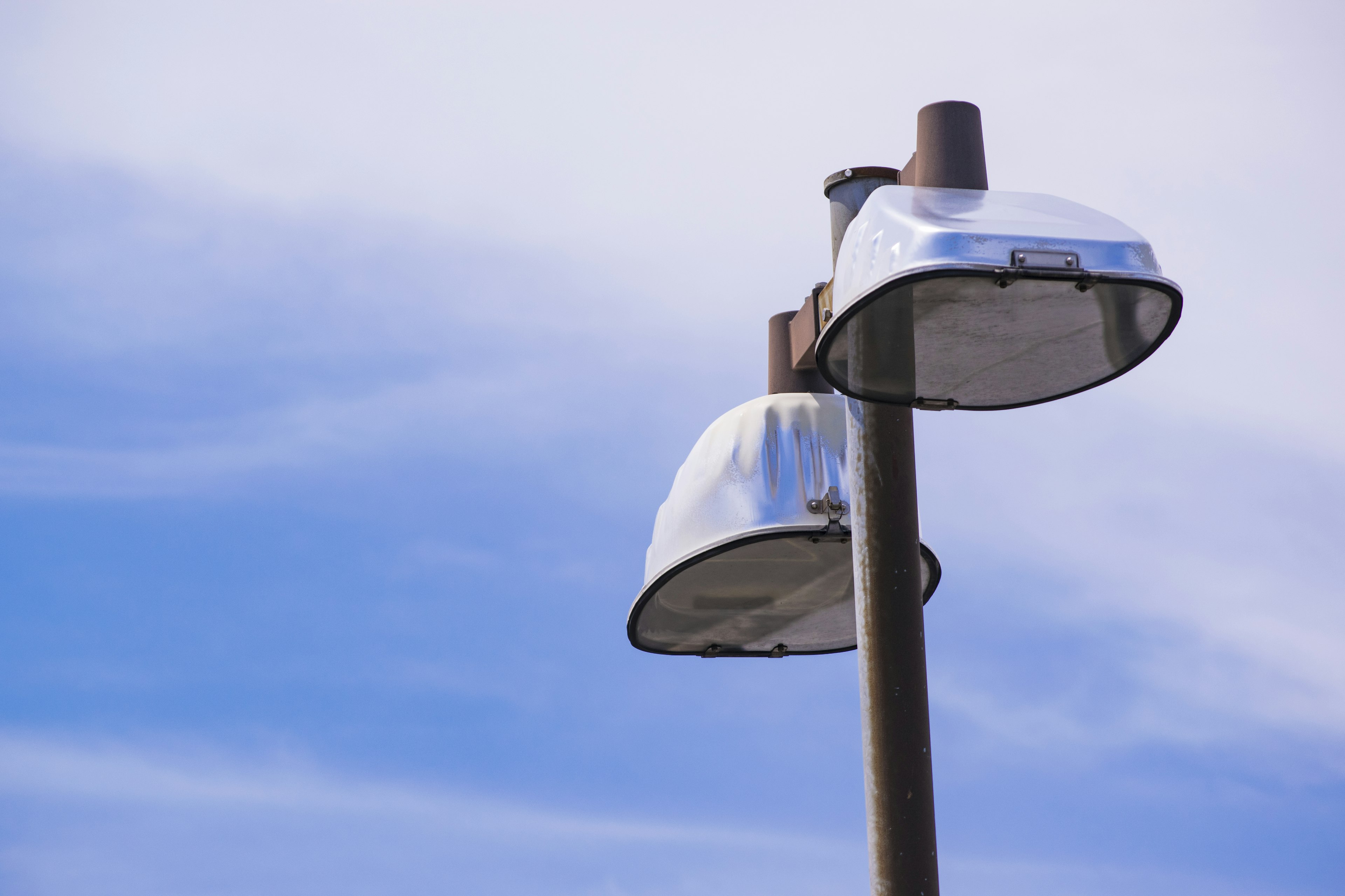 Streetlights with silver shades against a blue sky