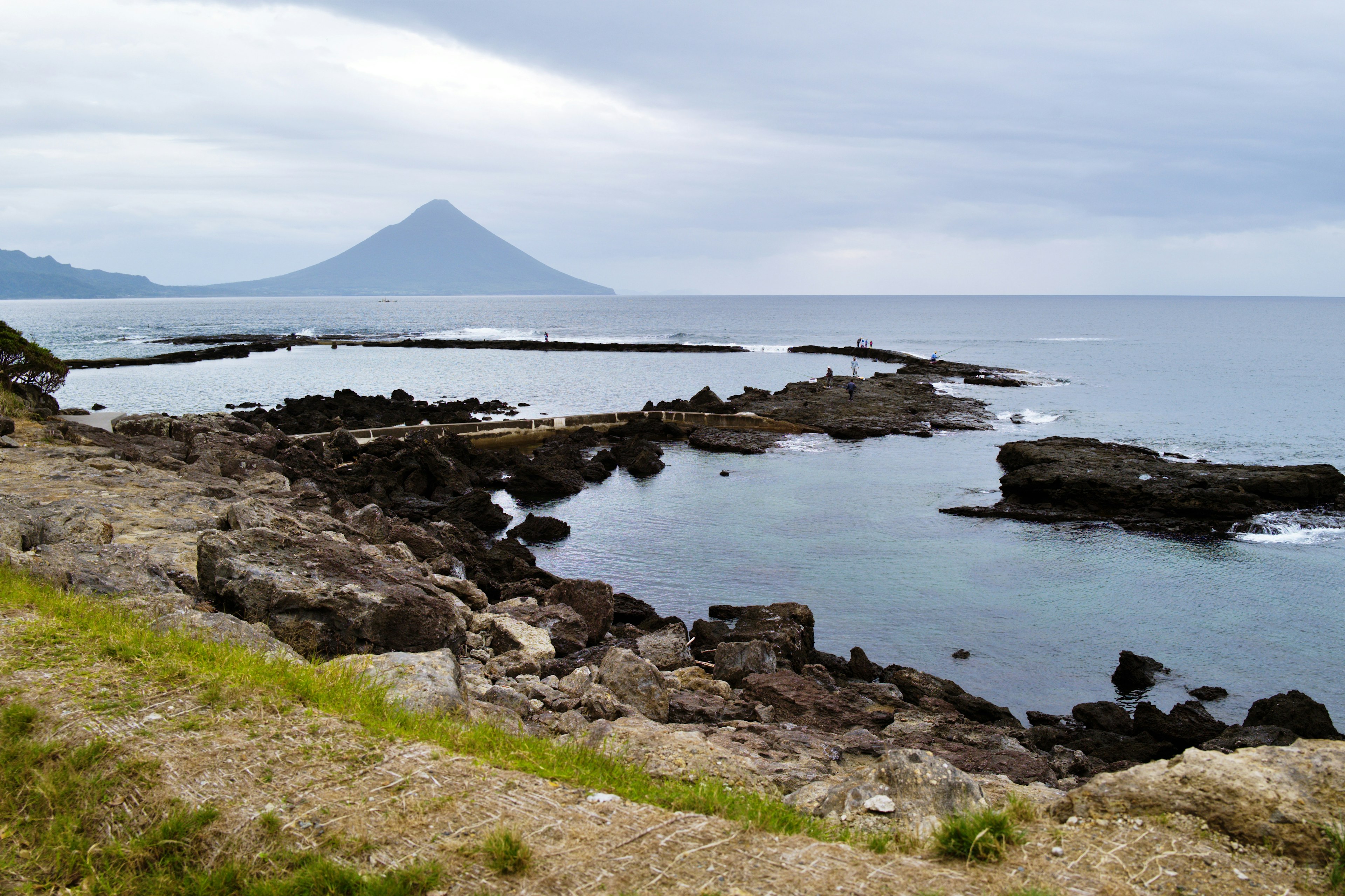 海岸線和岩石的風景，背景有一座山