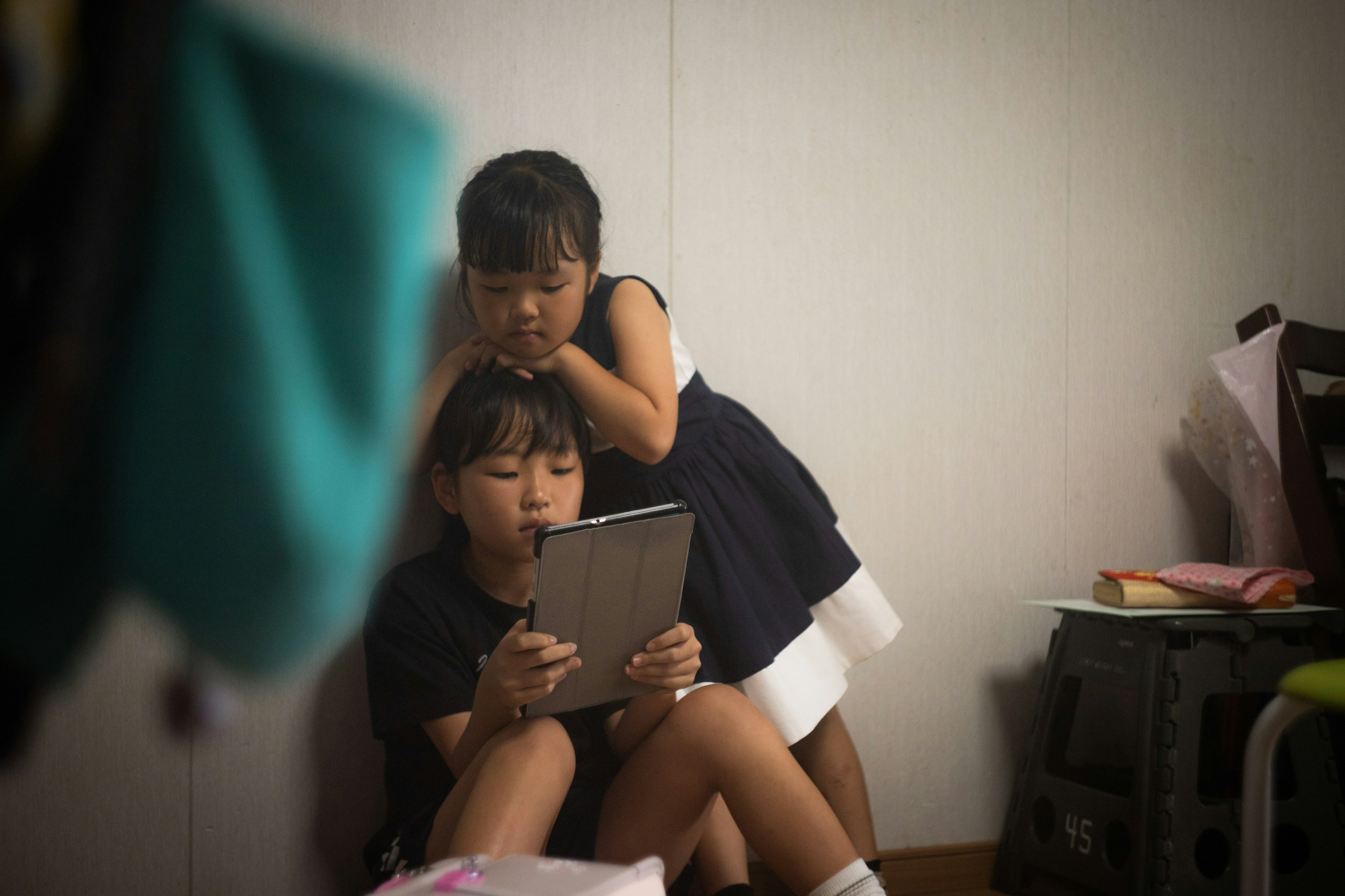 Two children looking at a tablet in a room