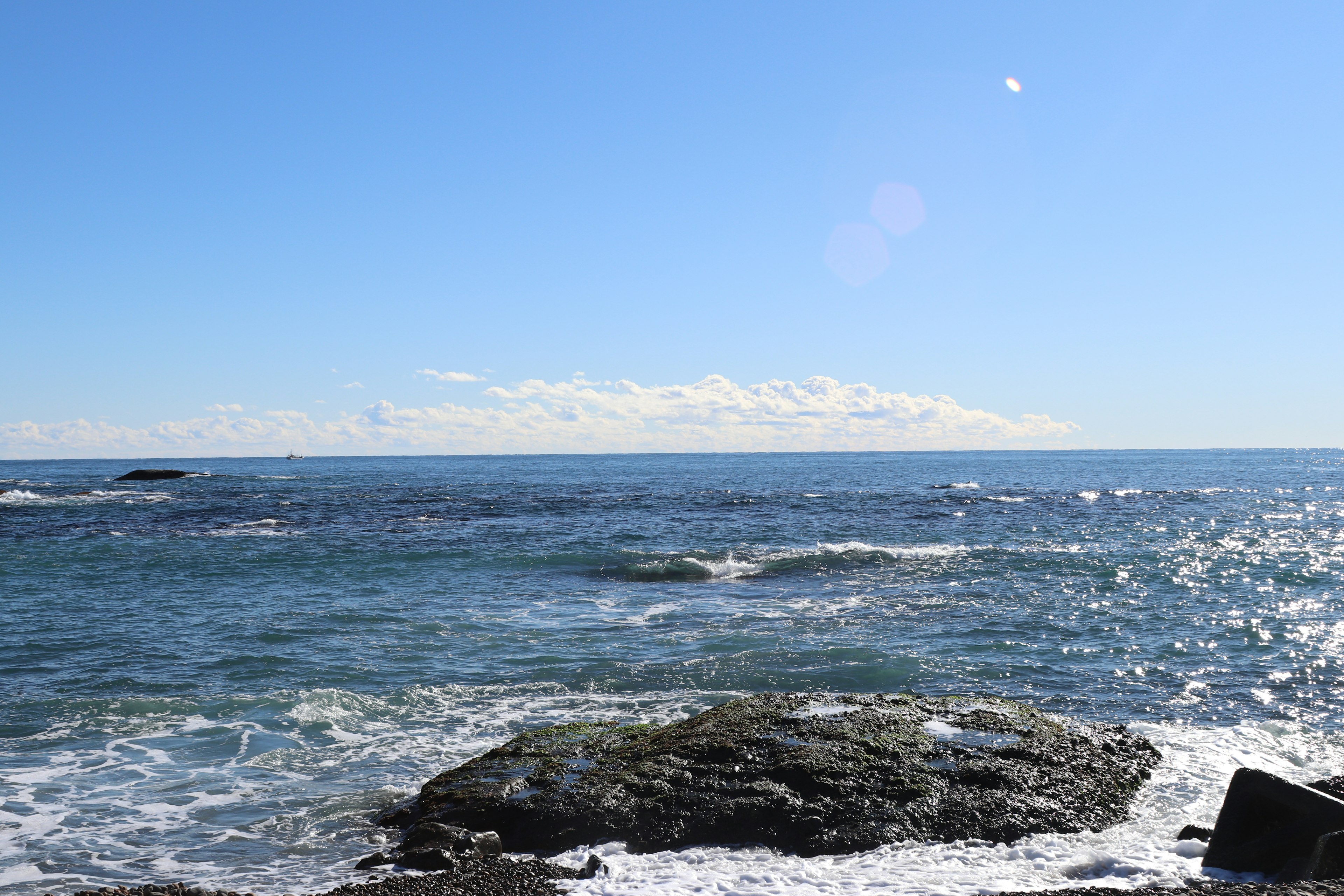 Vista panoramica di un oceano calmo sotto un cielo blu con rocce in primo piano