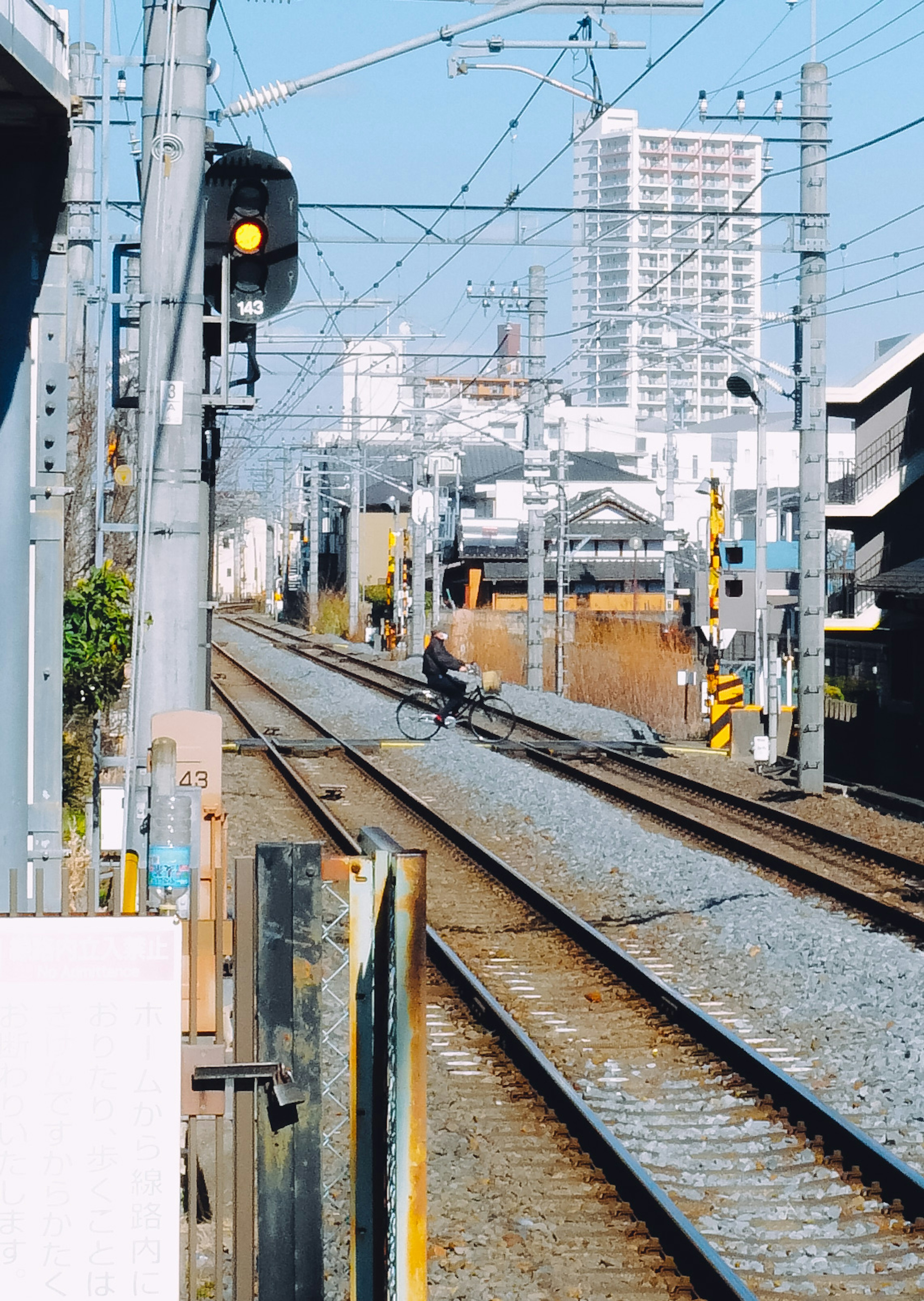 線路の先に信号機と建物が見える風景