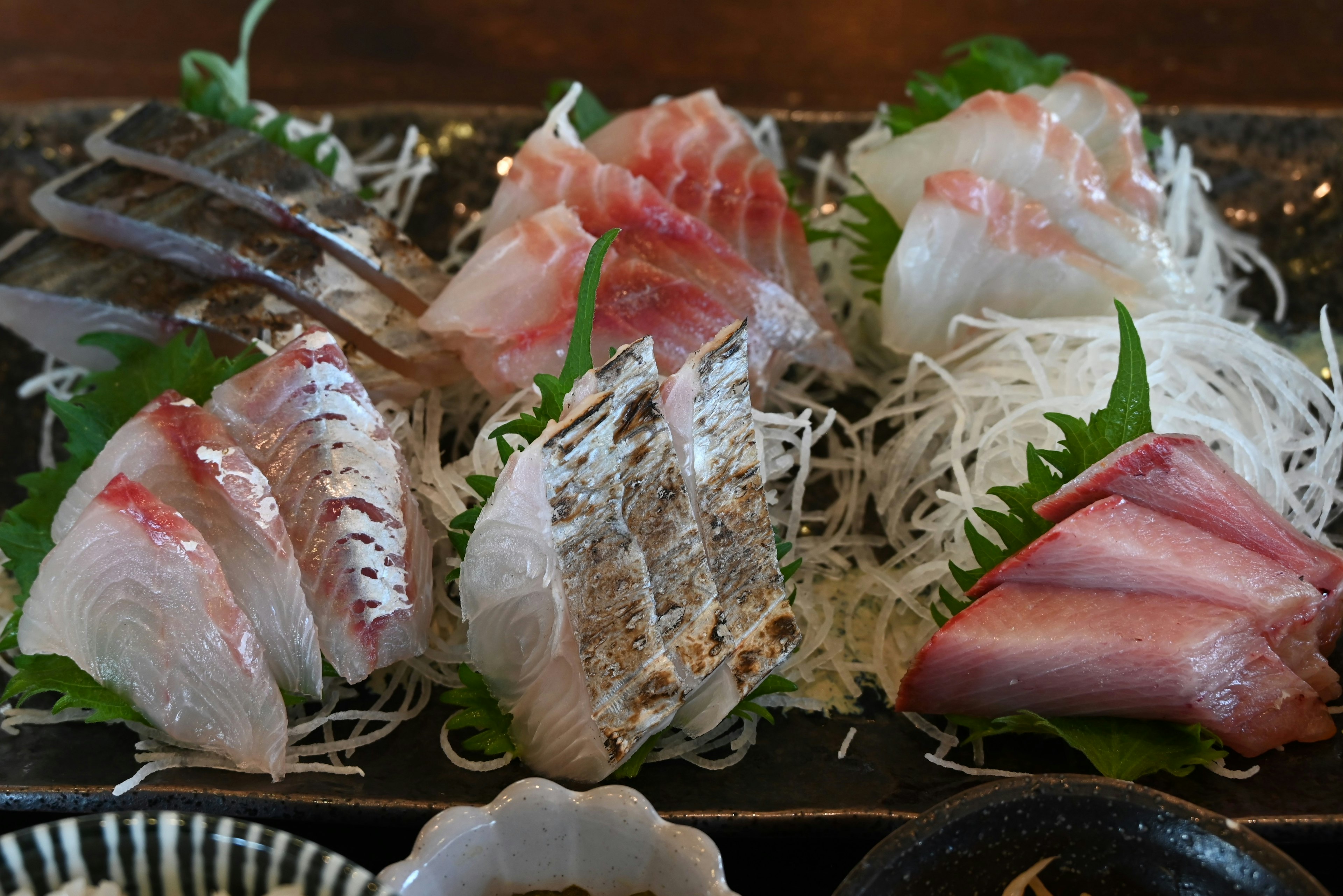 Đĩa sashimi tươi với củ cải trắng thái mỏng và rau xanh