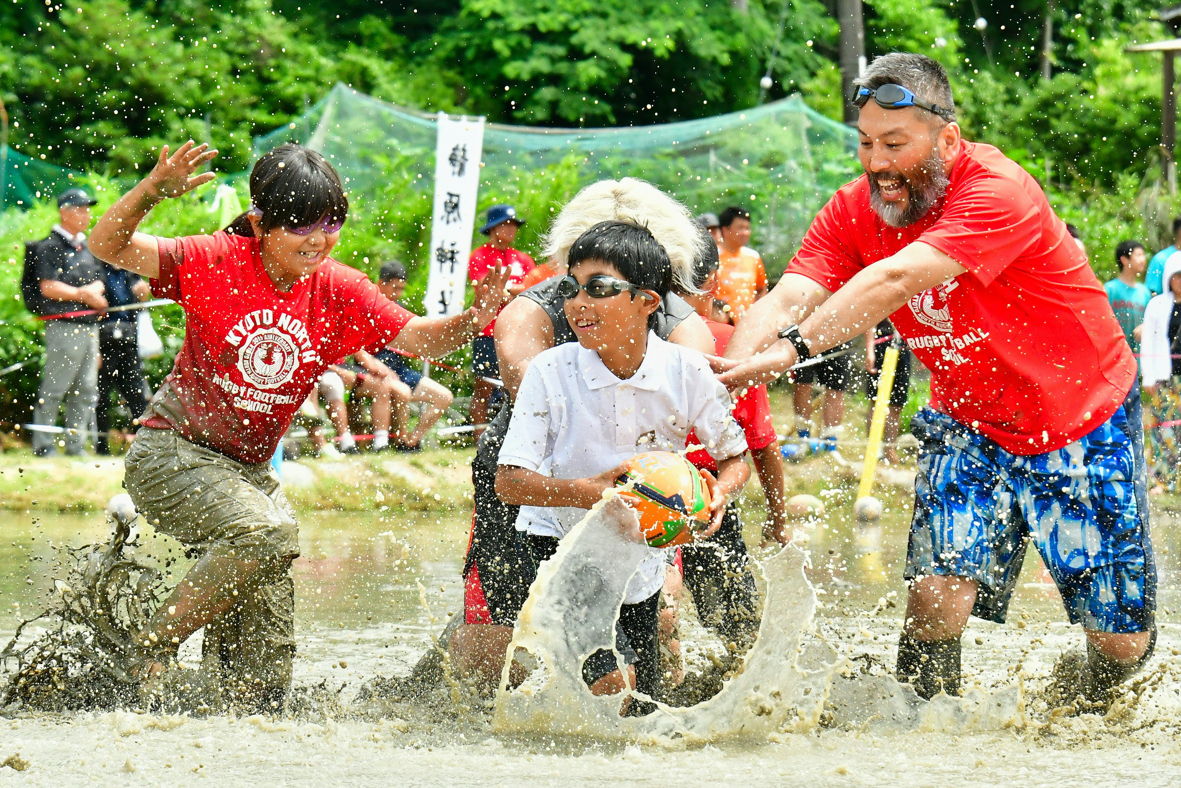 Kinder und Erwachsene spielen im Wasser und spritzen während eines Wettkampfs