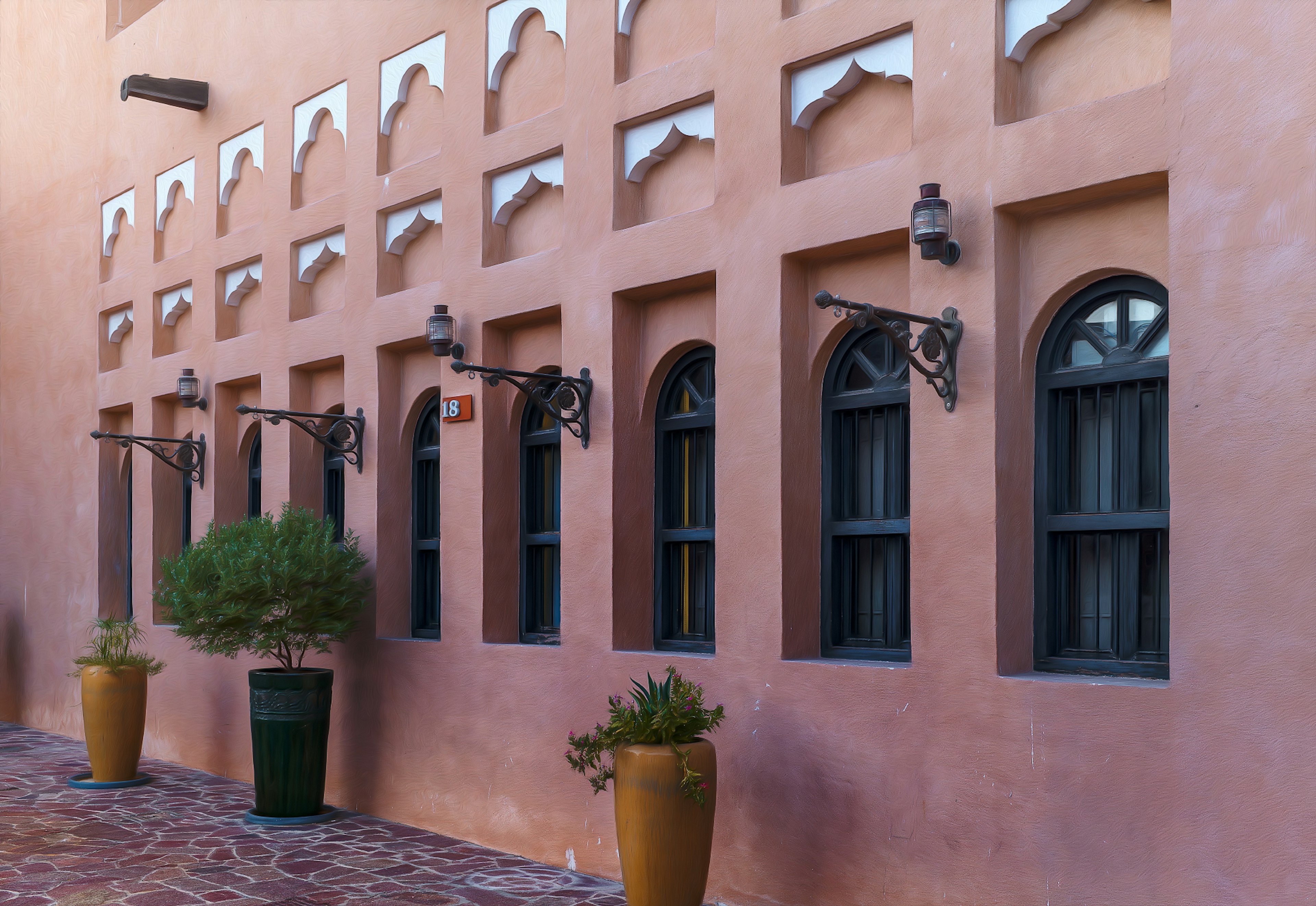 Exterior de un edificio con ventanas decorativas y plantas en una pared rosa