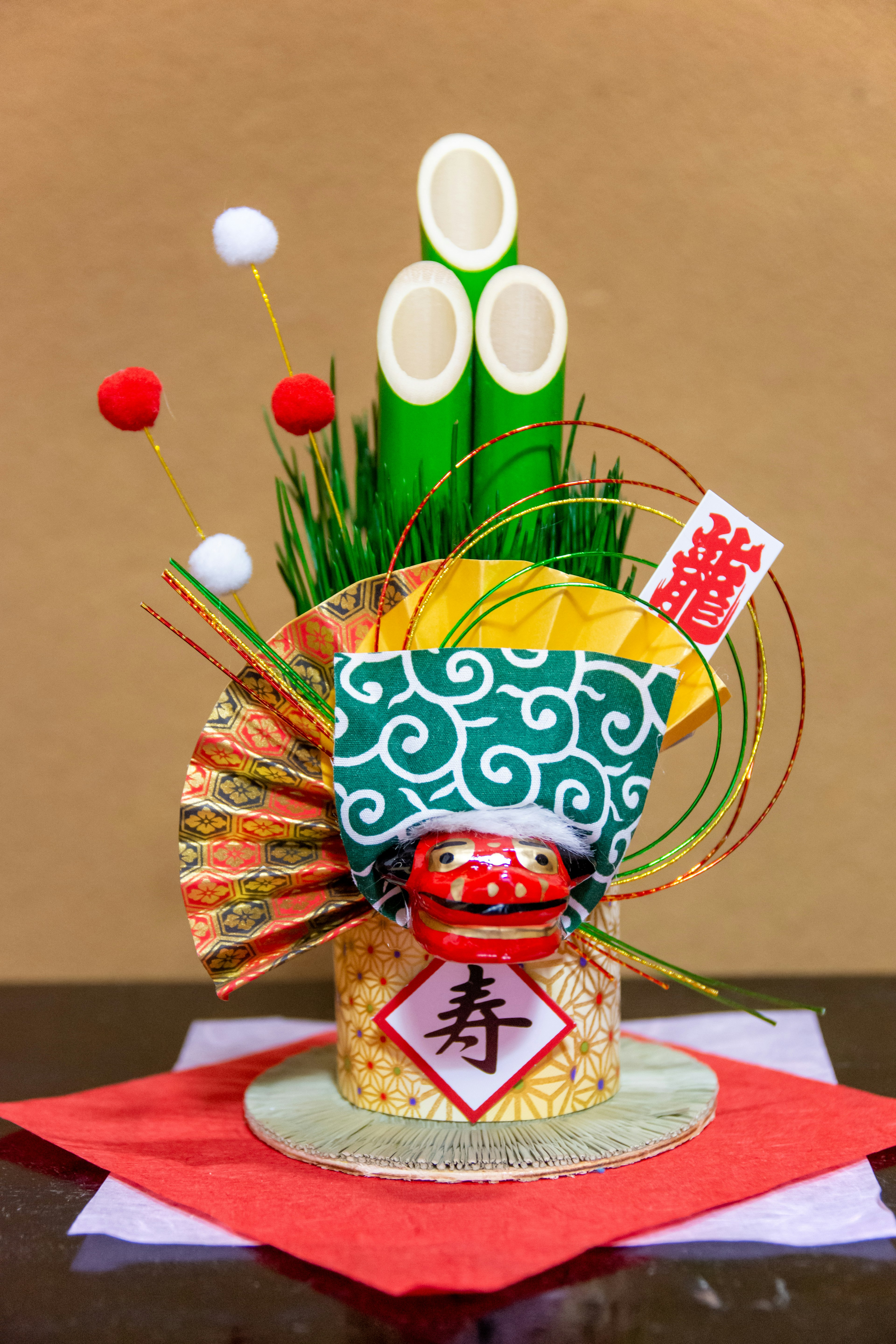 Decorazione giapponese per il Capodanno con foglie di bambù e pino e una bambola daruma rossa