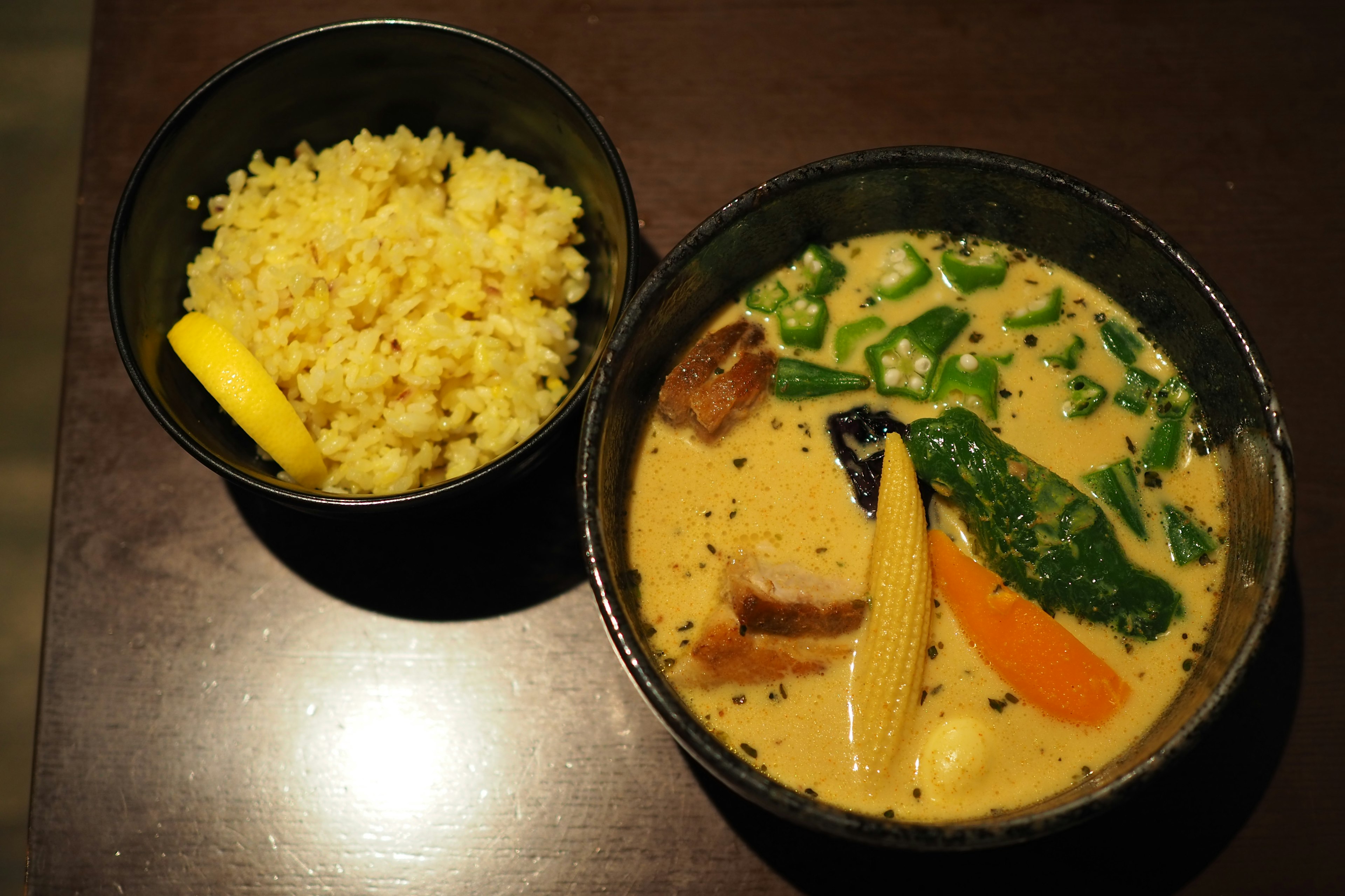 Soupe crémeuse avec des légumes colorés servie avec du riz jaune et une tranche de citron