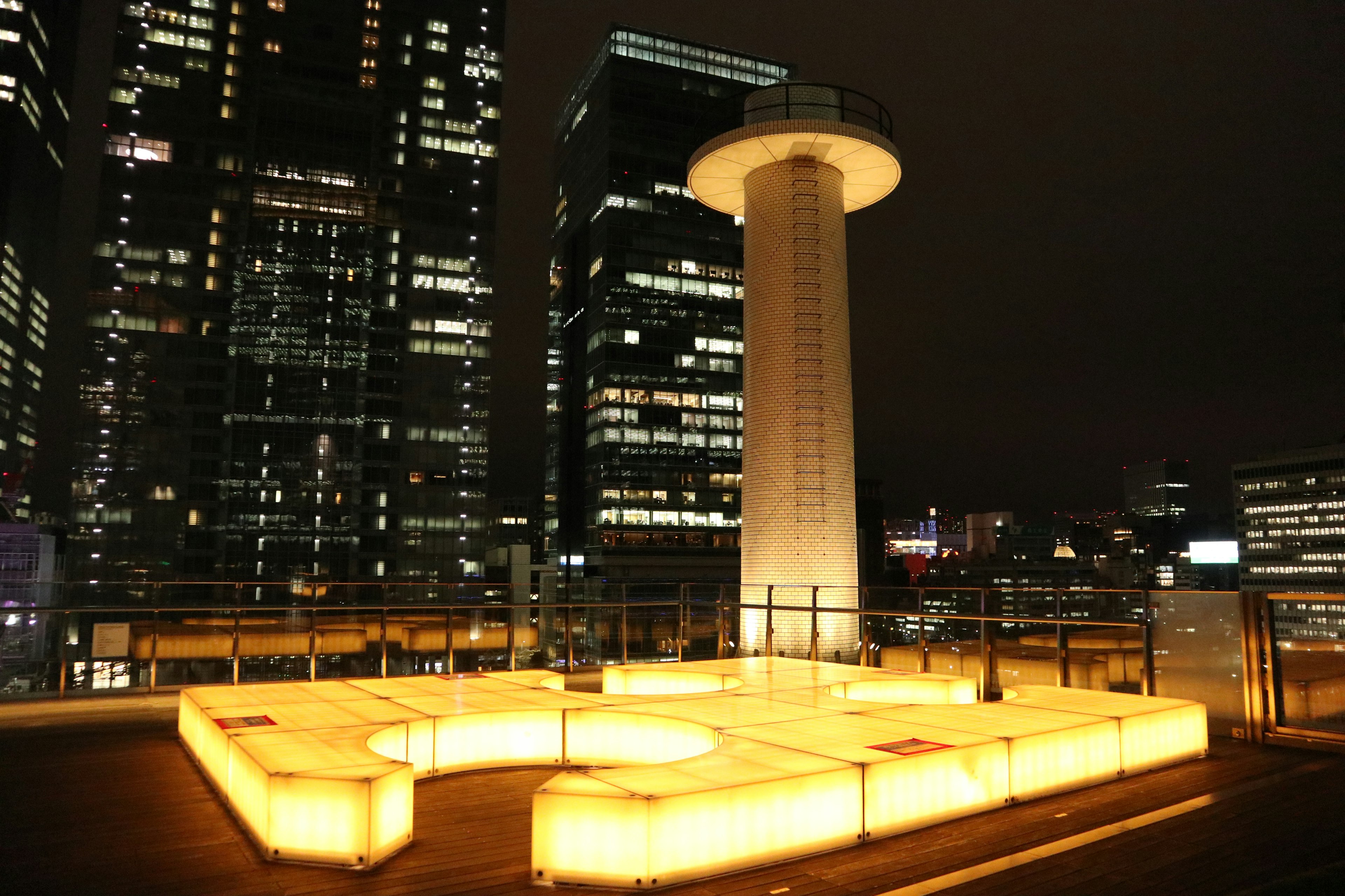 Rooftop structure illuminated with bright yellow lights in a night urban landscape