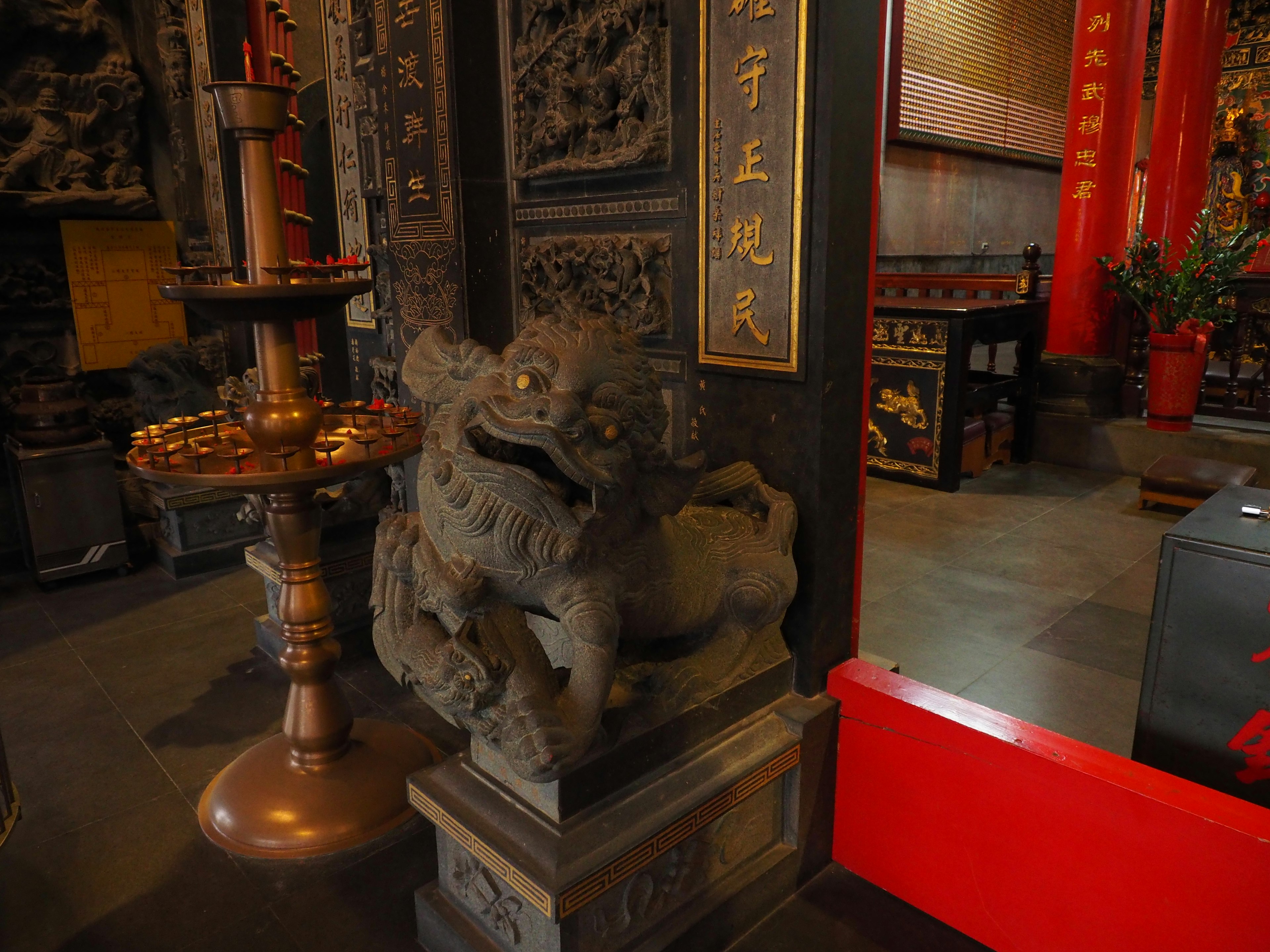 Statue de lion en pierre et décorations rouges à l'intérieur d'un temple