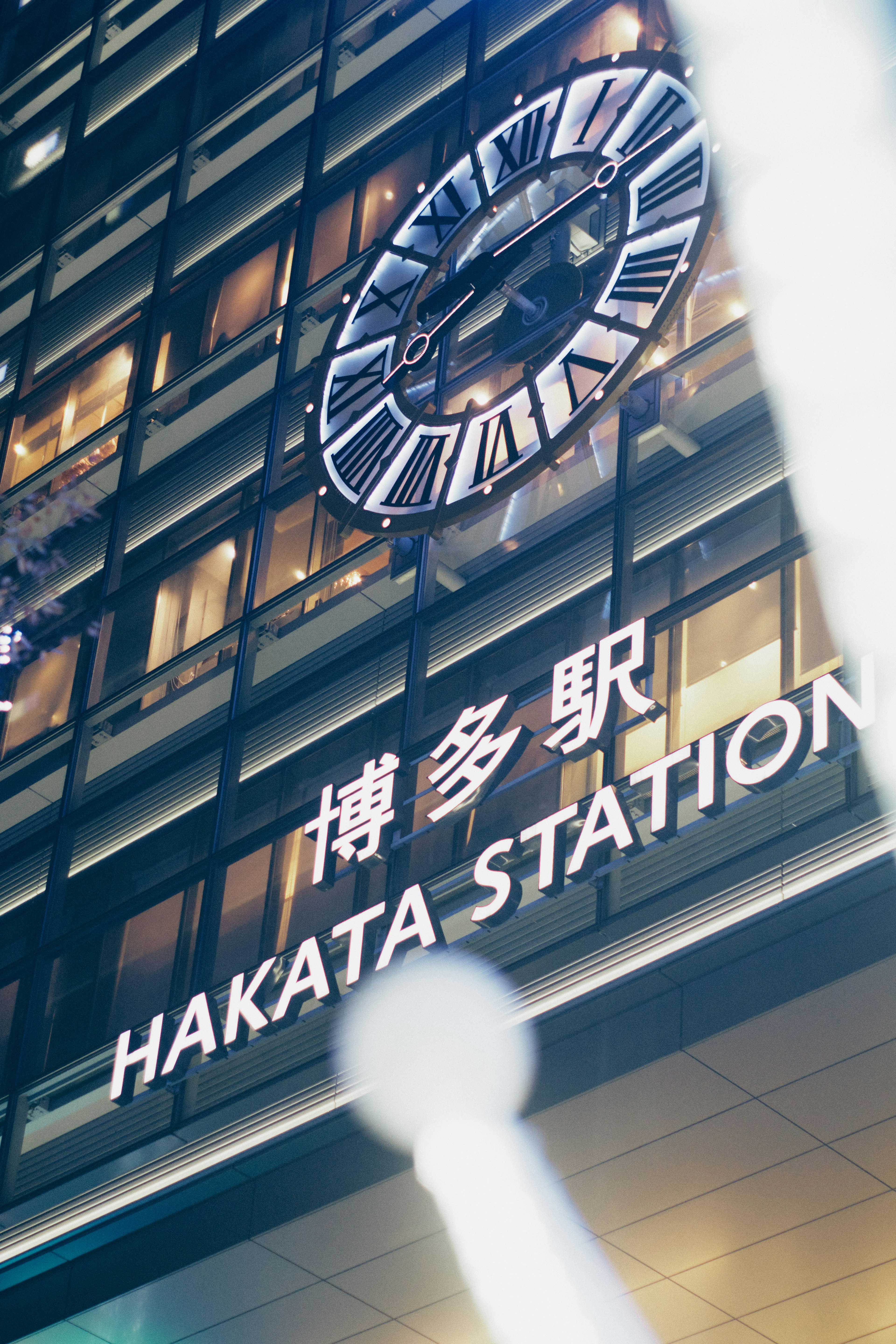 Vue nocturne du bâtiment de la gare de Hakata avec une horloge