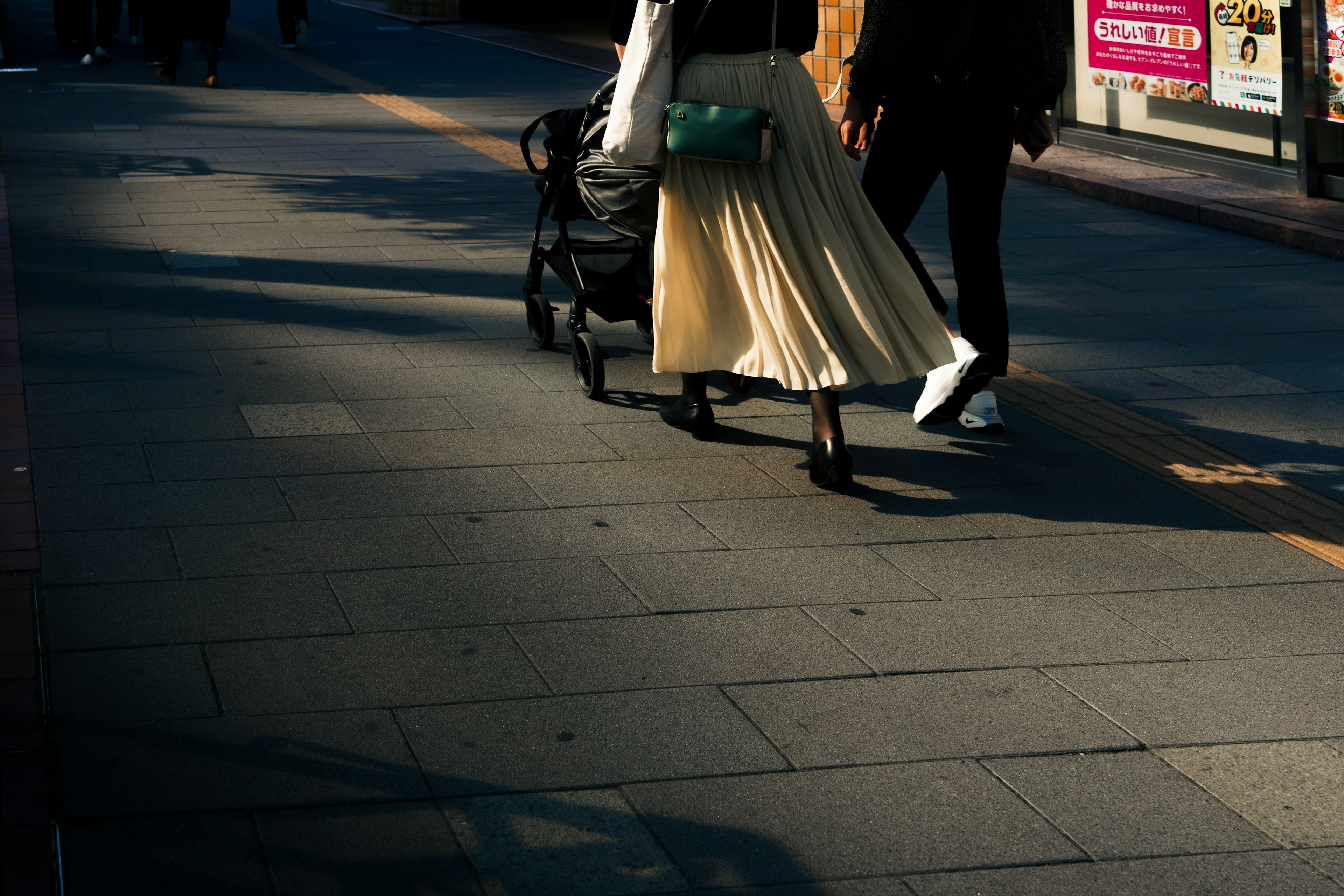 People walking in a street with a stroller and a flowing skirt