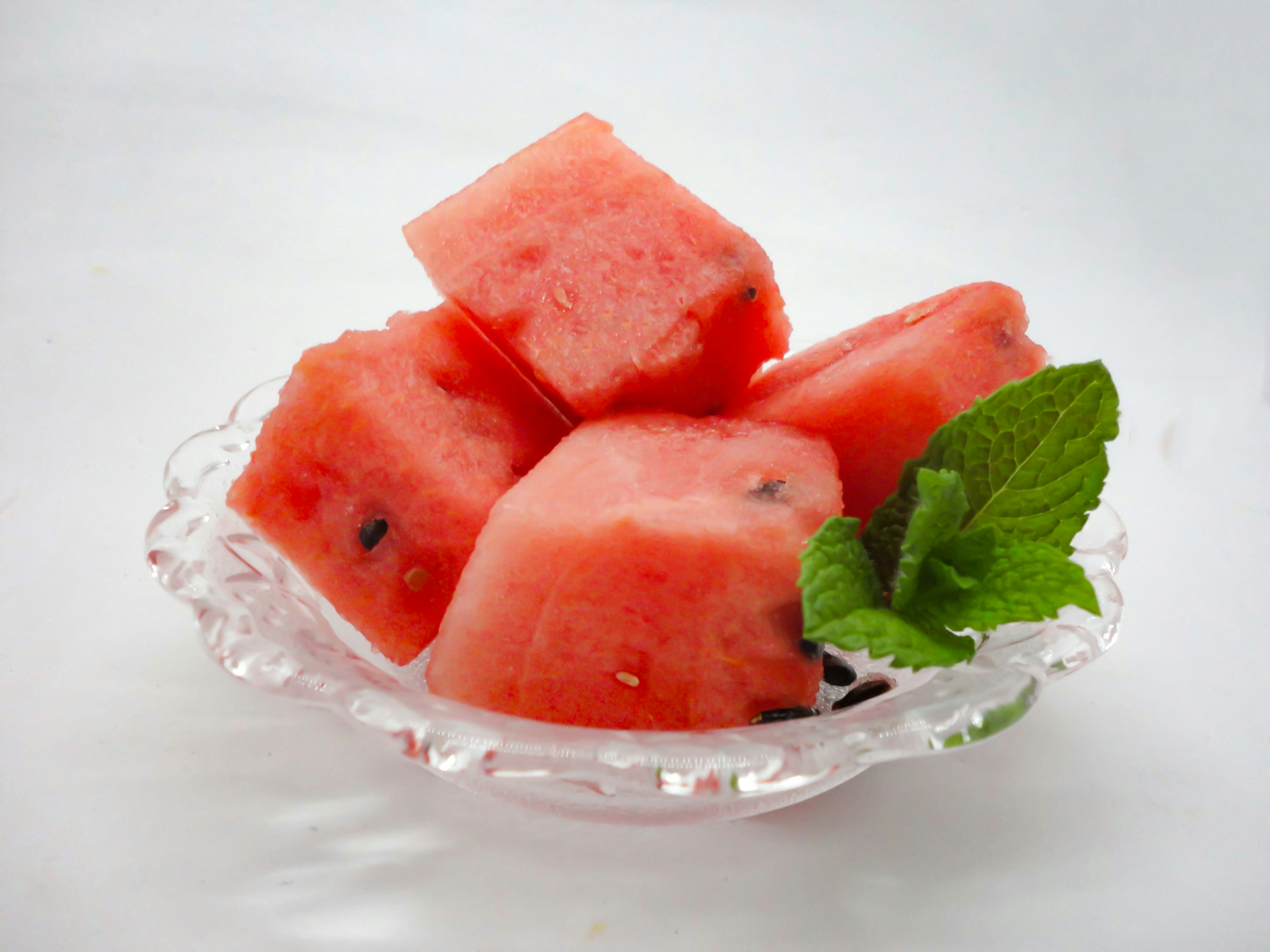 Cubed watermelon pieces with mint leaves in a clear dish