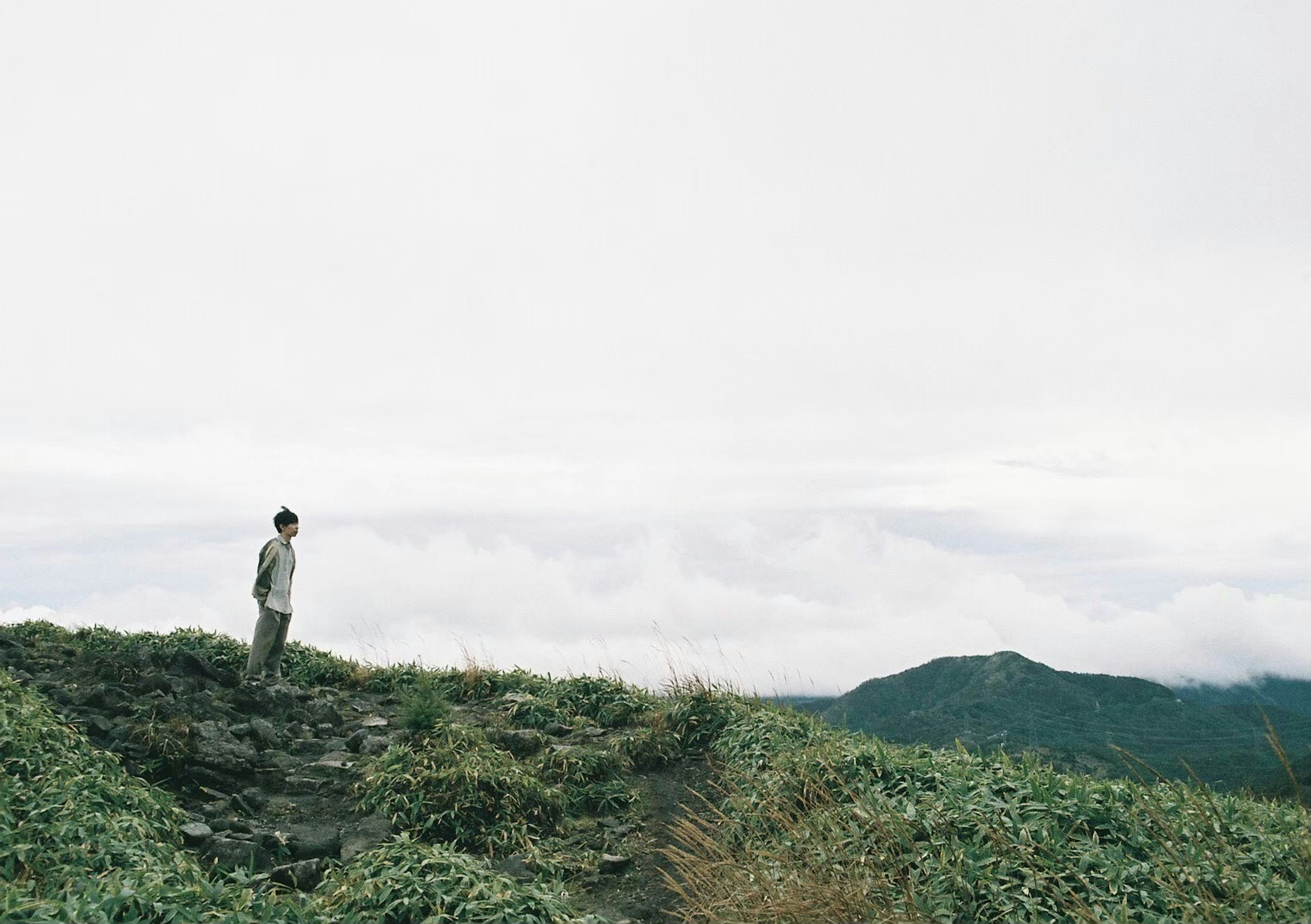 Un hombre de pie en la cima de una montaña mirando un mar de nubes