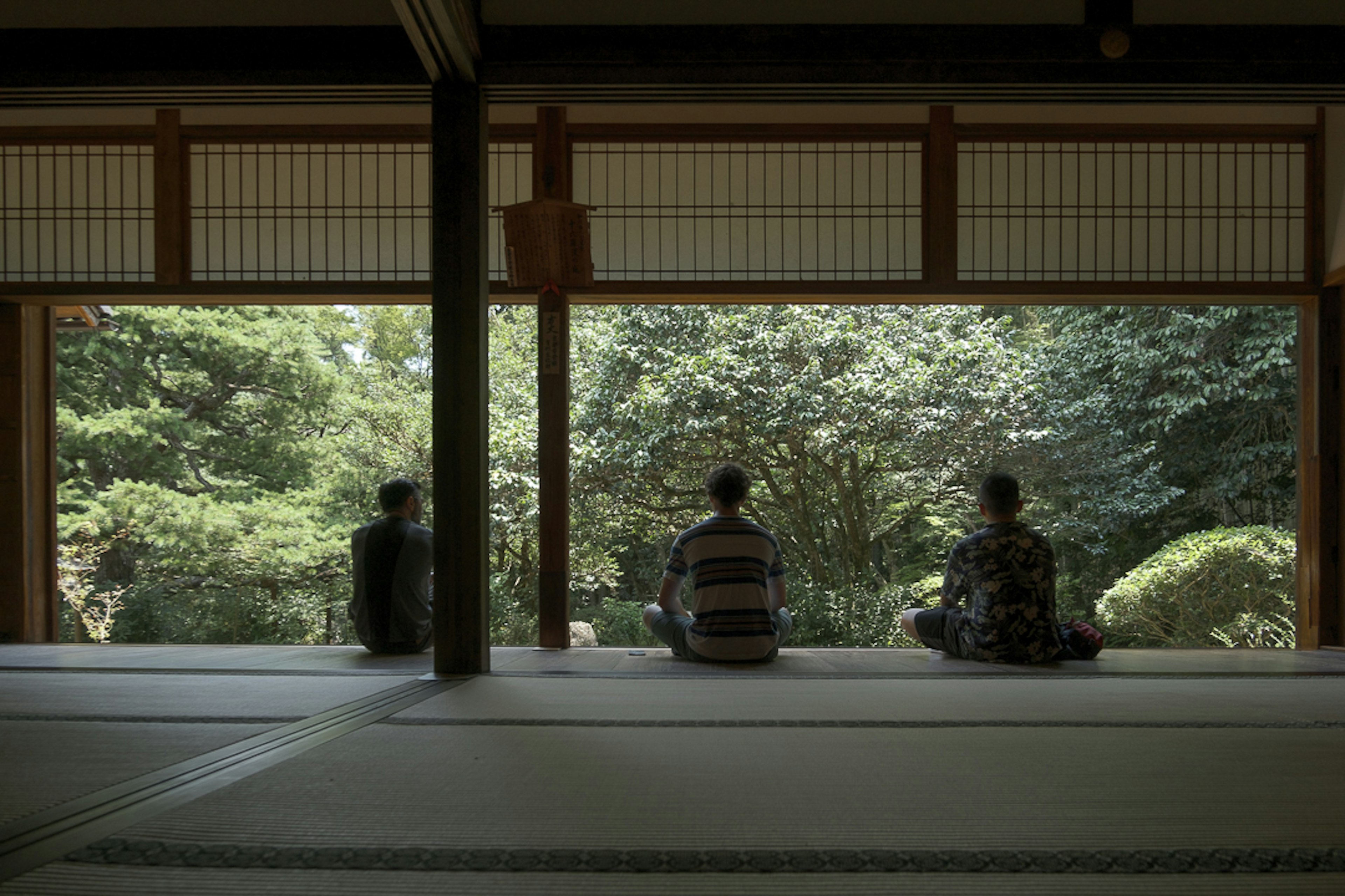 三個人坐在傳統日本房間中，俯瞰寧靜的花園