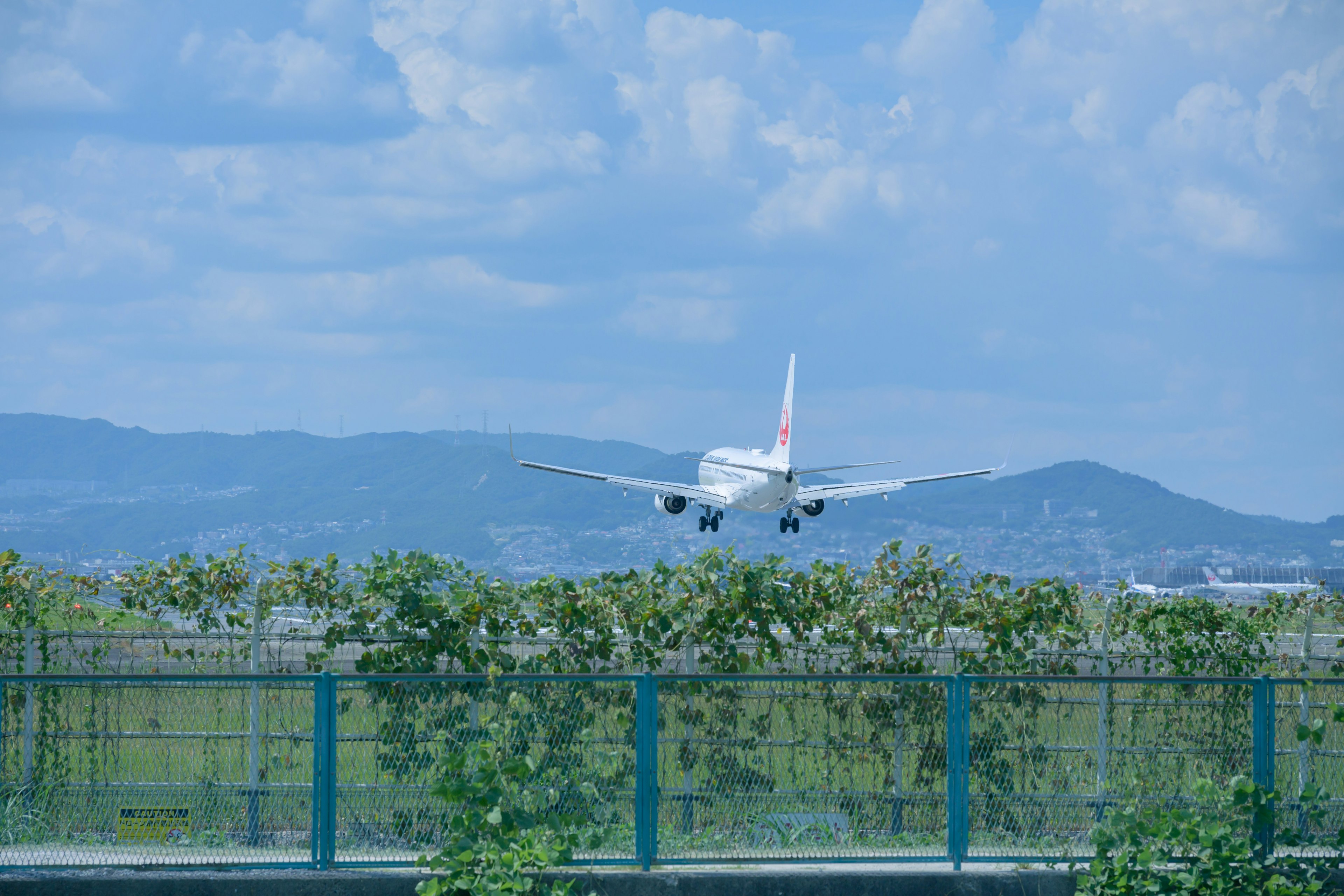 Flugzeug landet unter blauem Himmel mit Bergen im Hintergrund