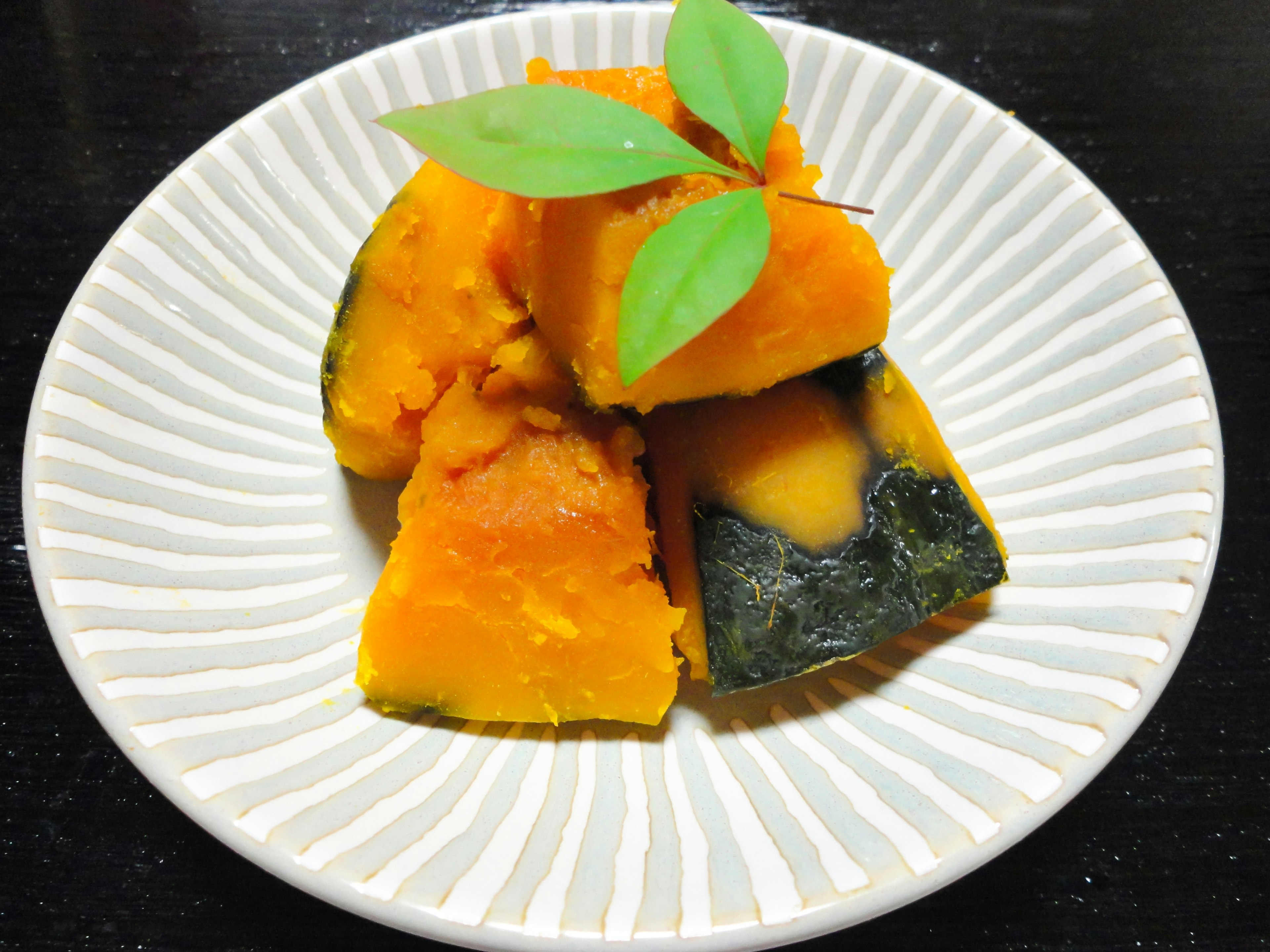 Steamed pumpkin pieces garnished with green leaves on a plate