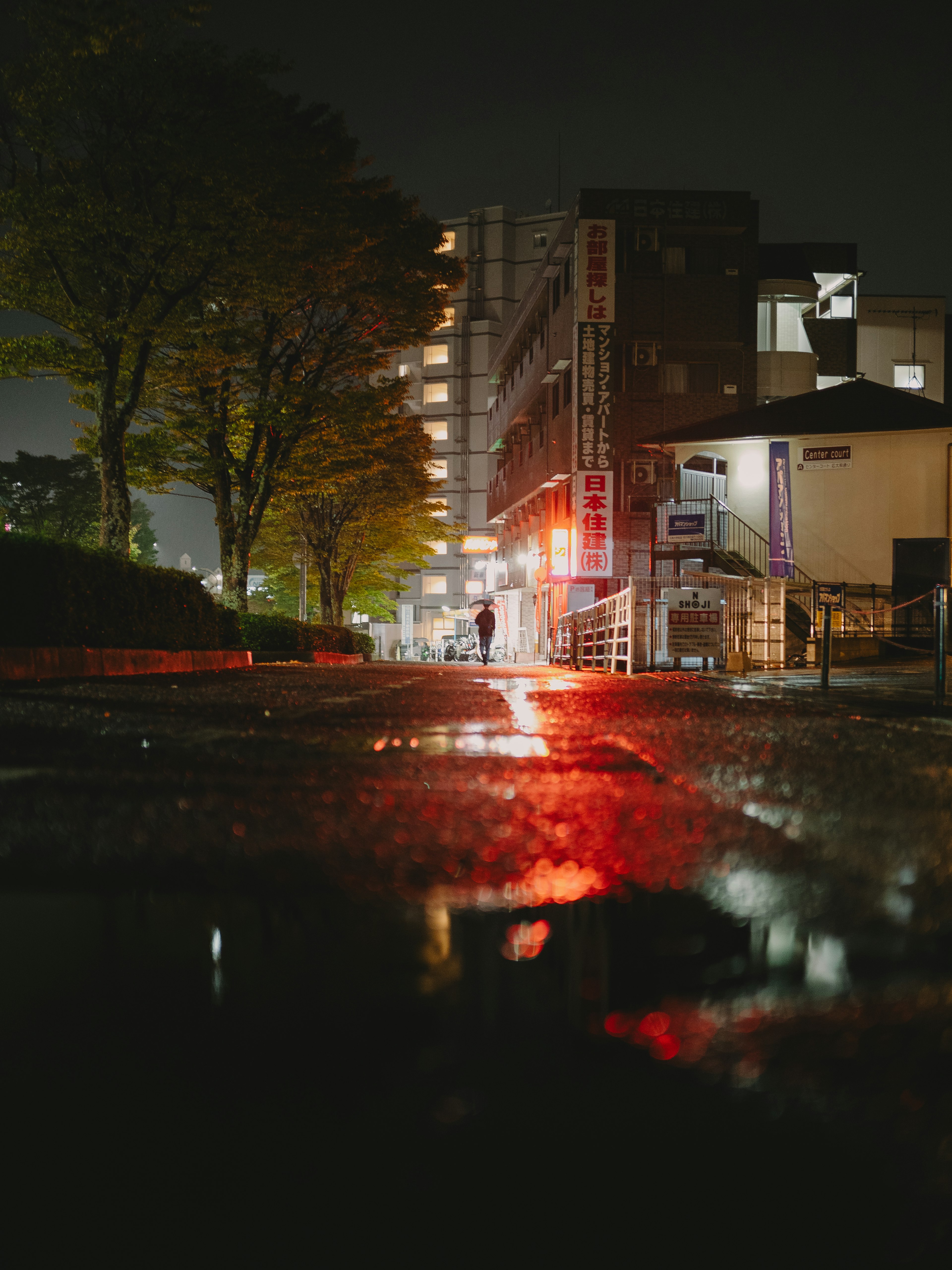 Paysage urbain nocturne avec des reflets rouges sur le pavé mouillé