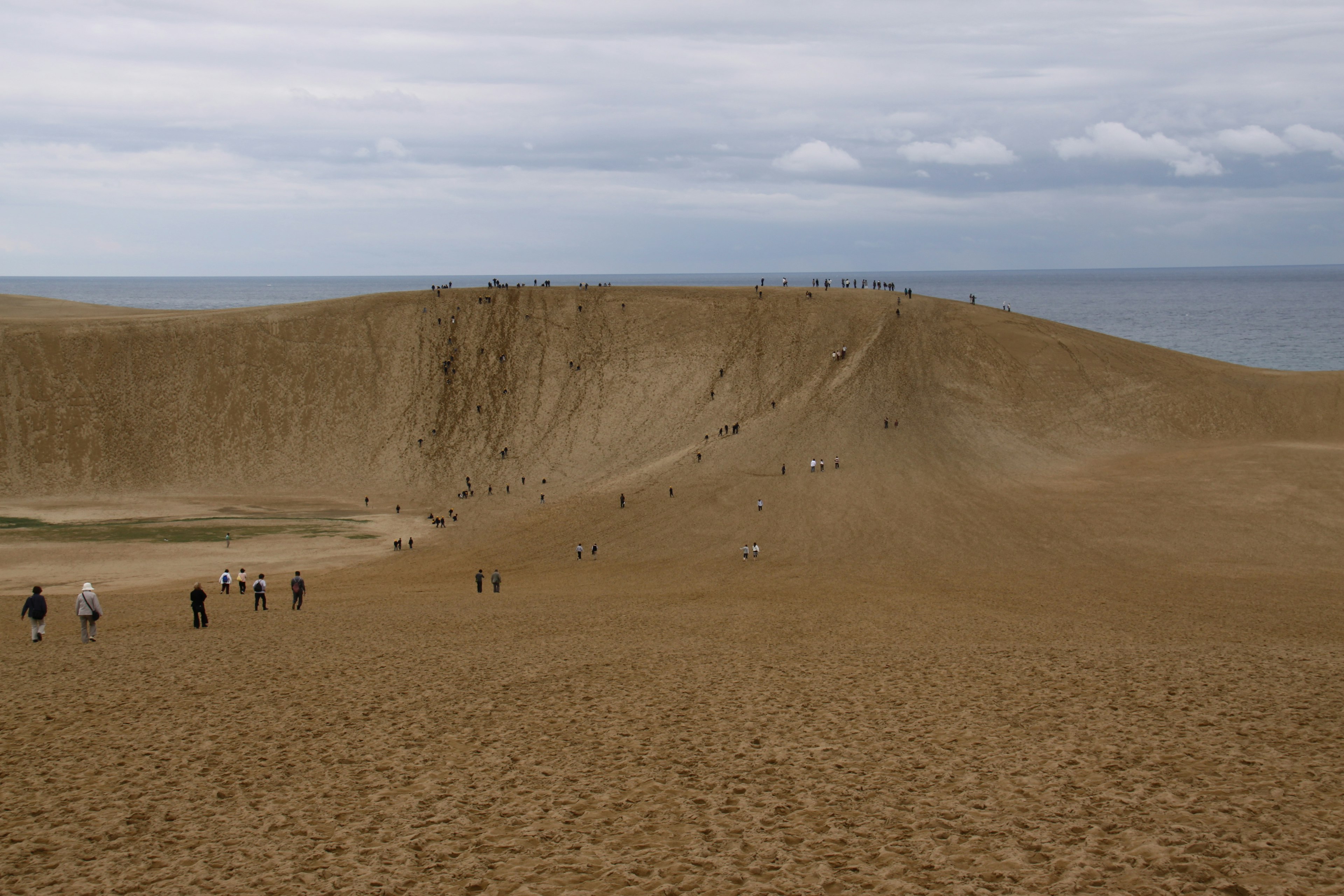 Large sand dune facing the sea with people