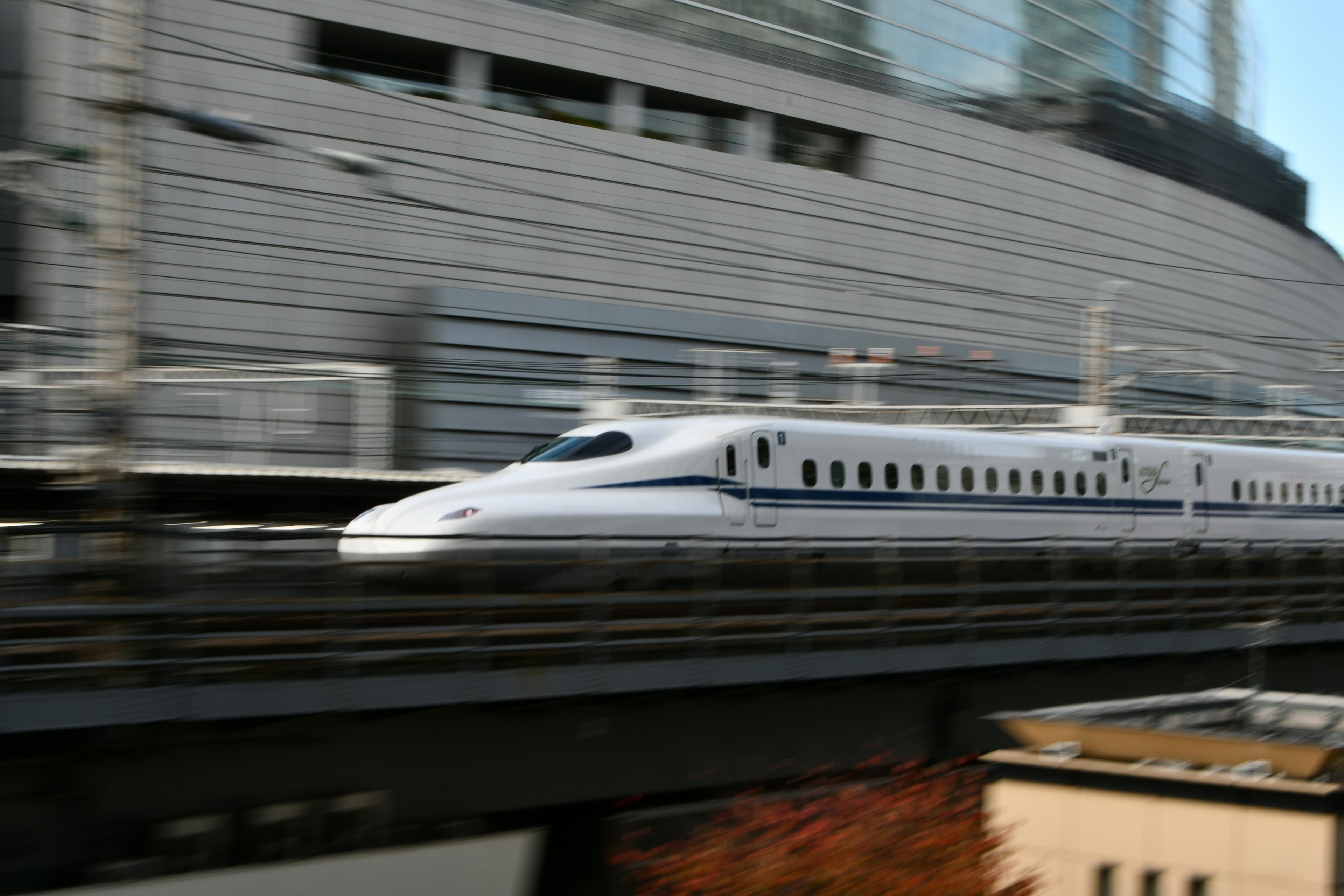 Shinkansen speeding past a modern urban backdrop