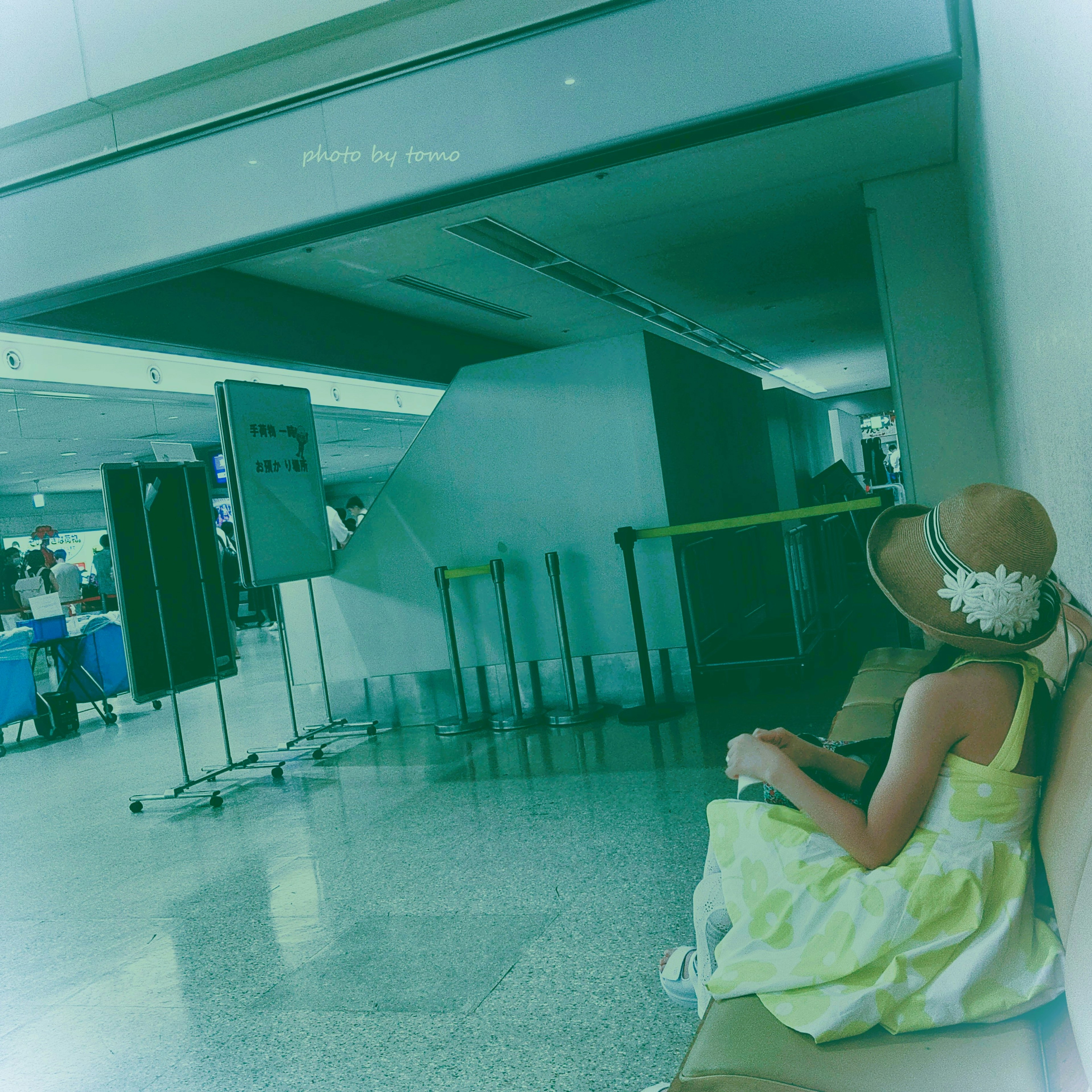 A woman sitting in an airport lounge wearing a yellow dress