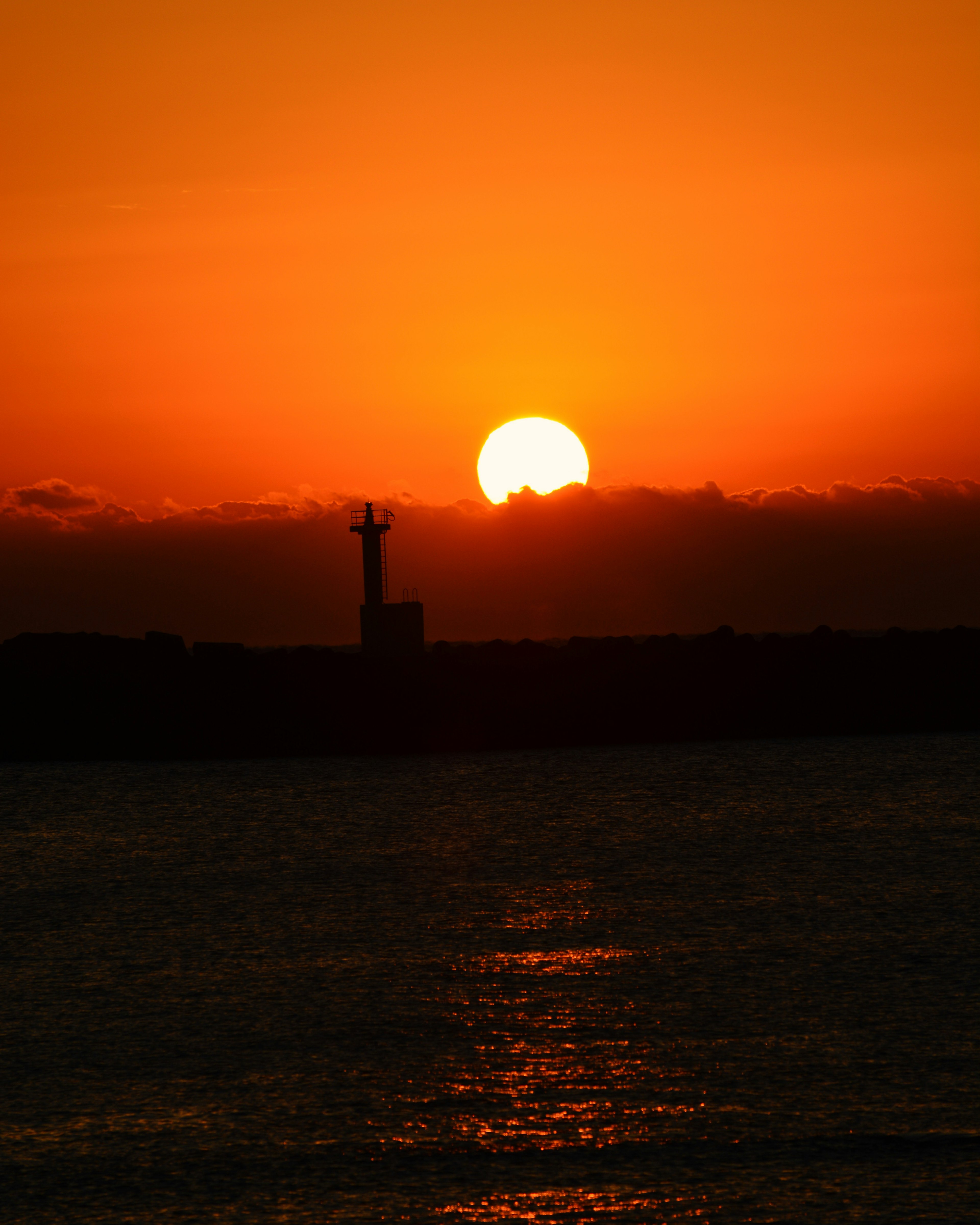 Schöner Sonnenuntergang über dem Meer mit Silhouette eines Leuchtturms