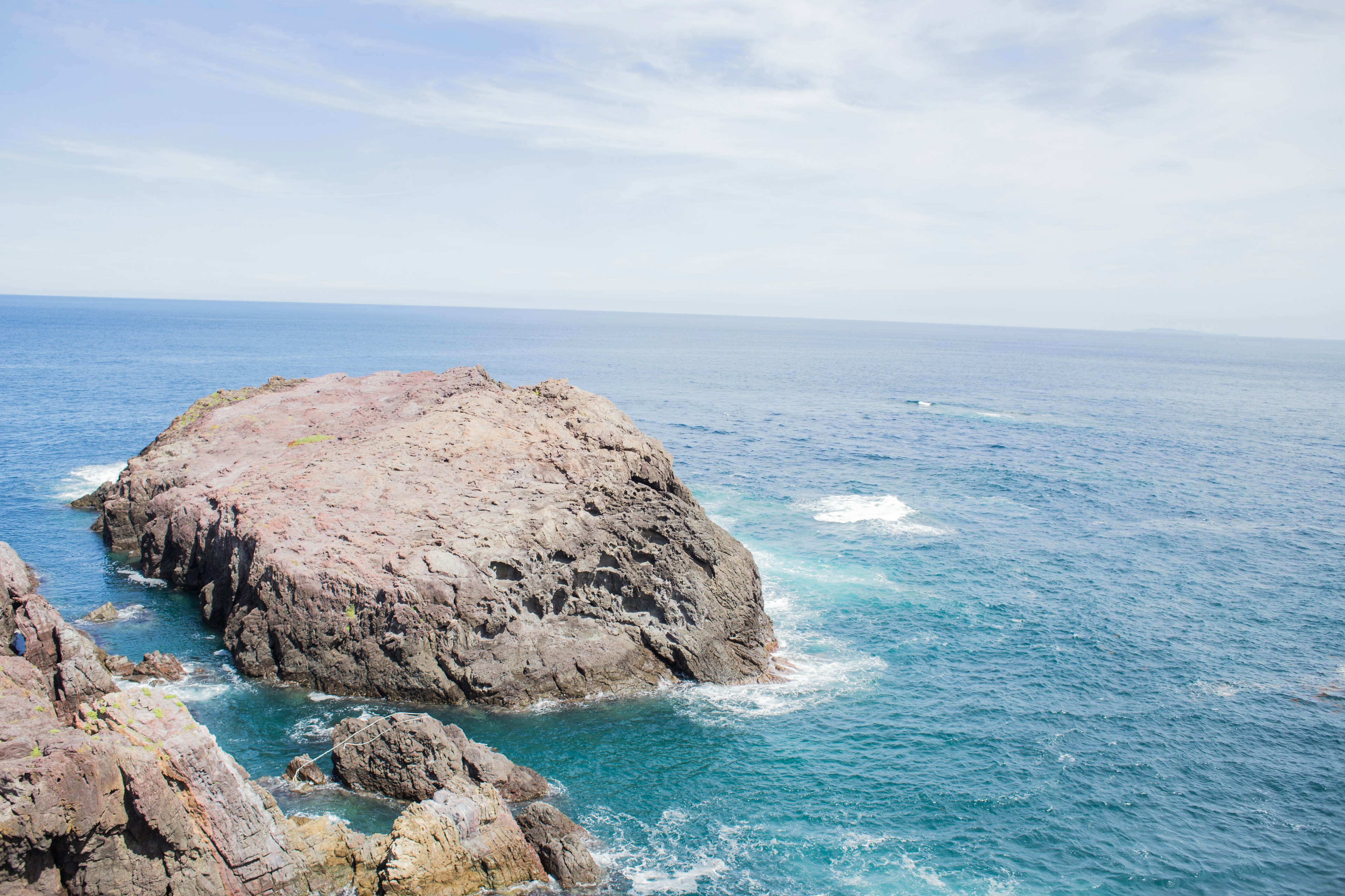 Paisaje costero con mar azul y roca prominente