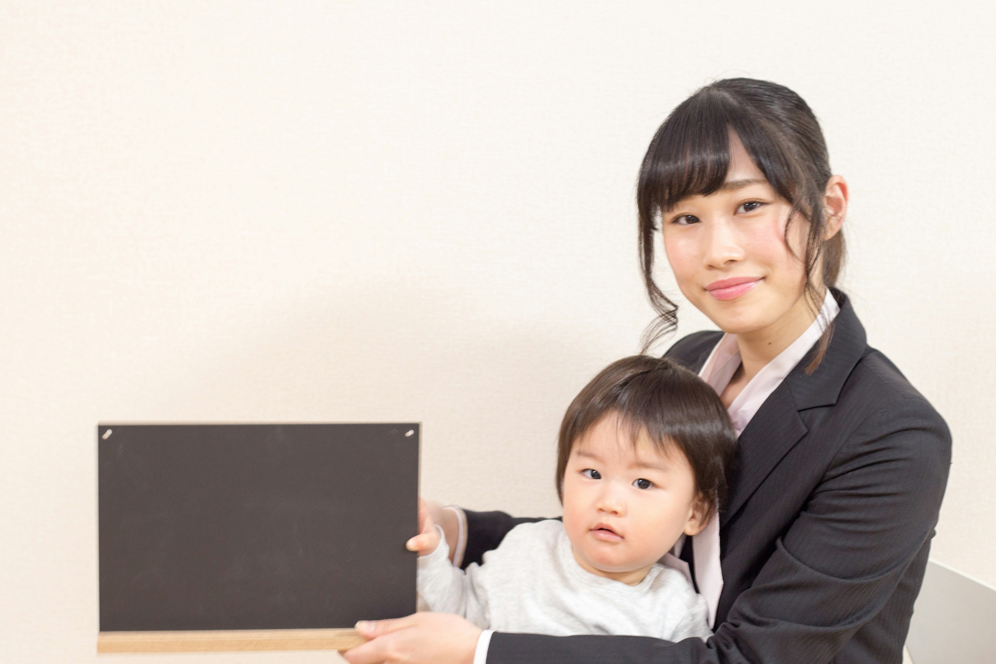 Portrait of a woman holding a black board with a child