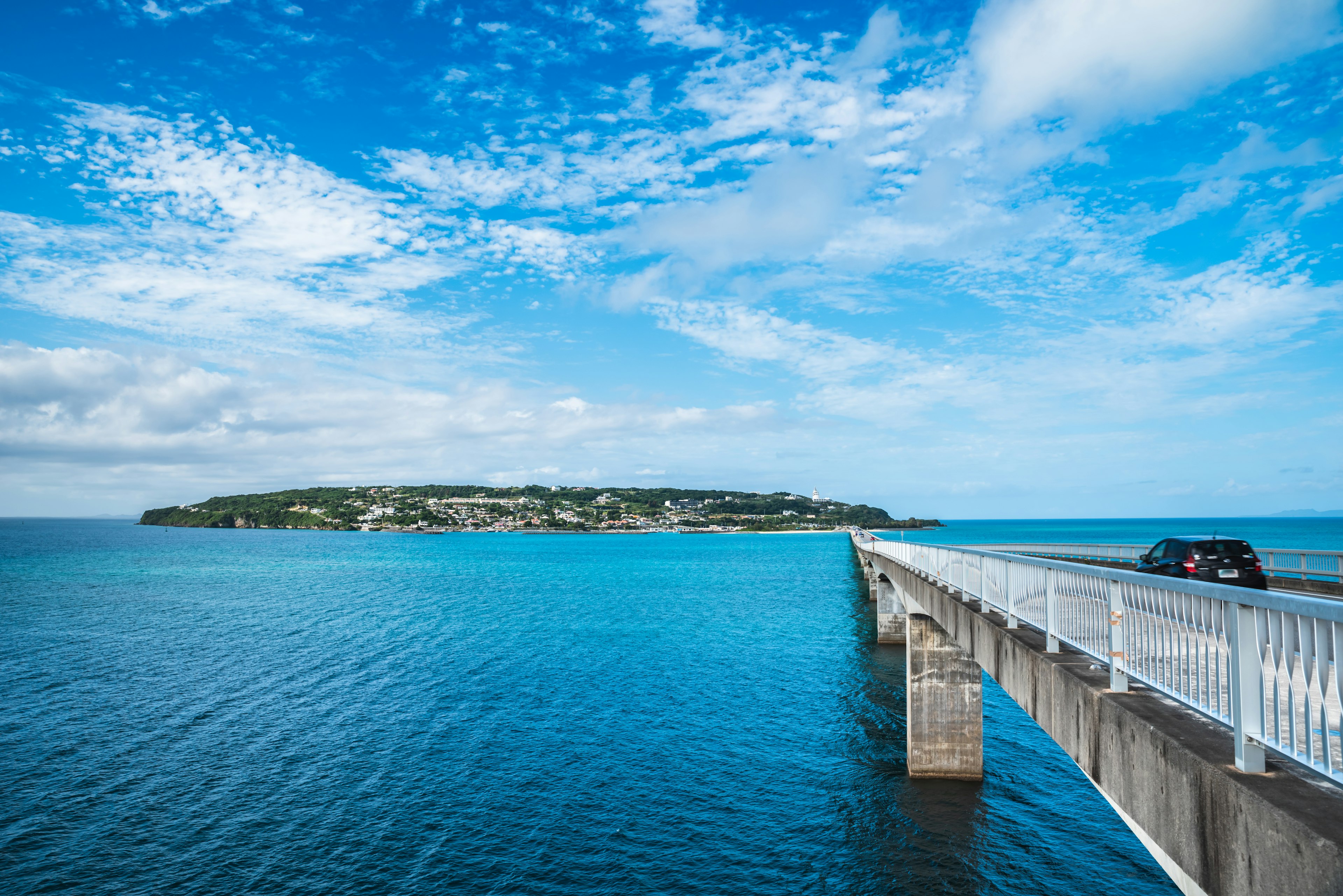 A scenic view of a bridge extending into turquoise waters with an island in the background