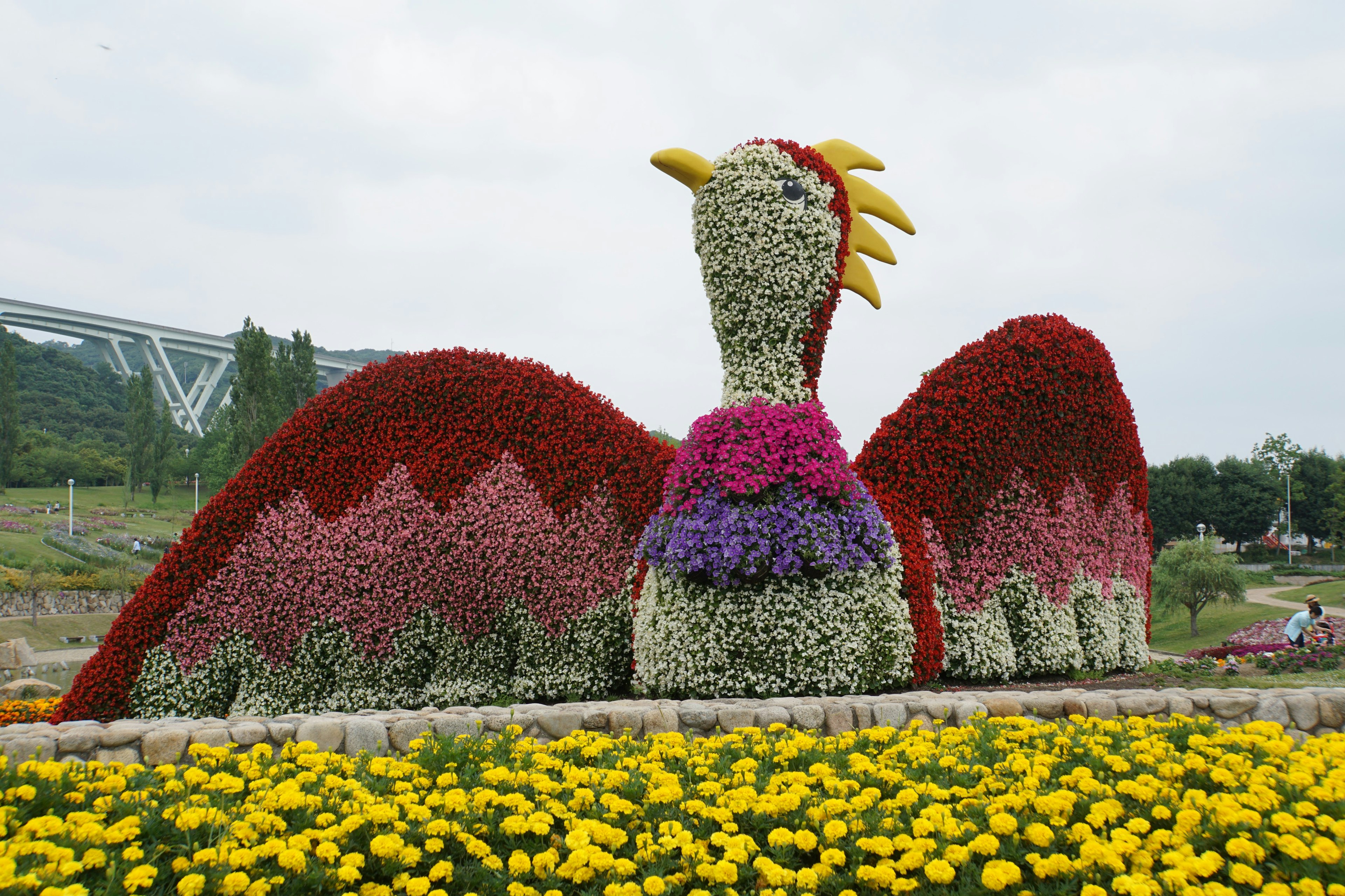 Grande sculpture d'oiseau en fleurs colorées dans un jardin