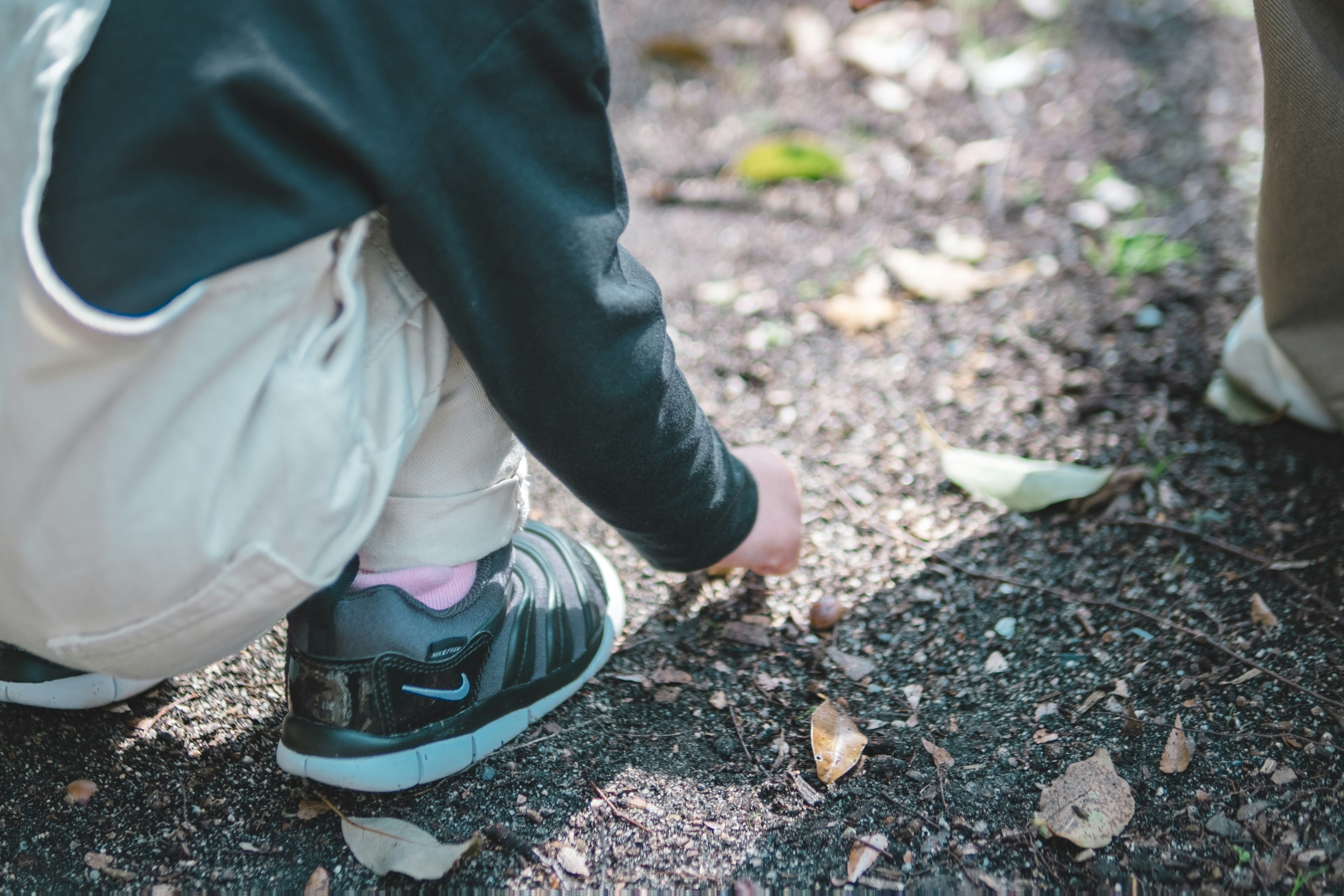 Un enfant ramassant des feuilles par terre gros plan des mains portant des chaussures noires