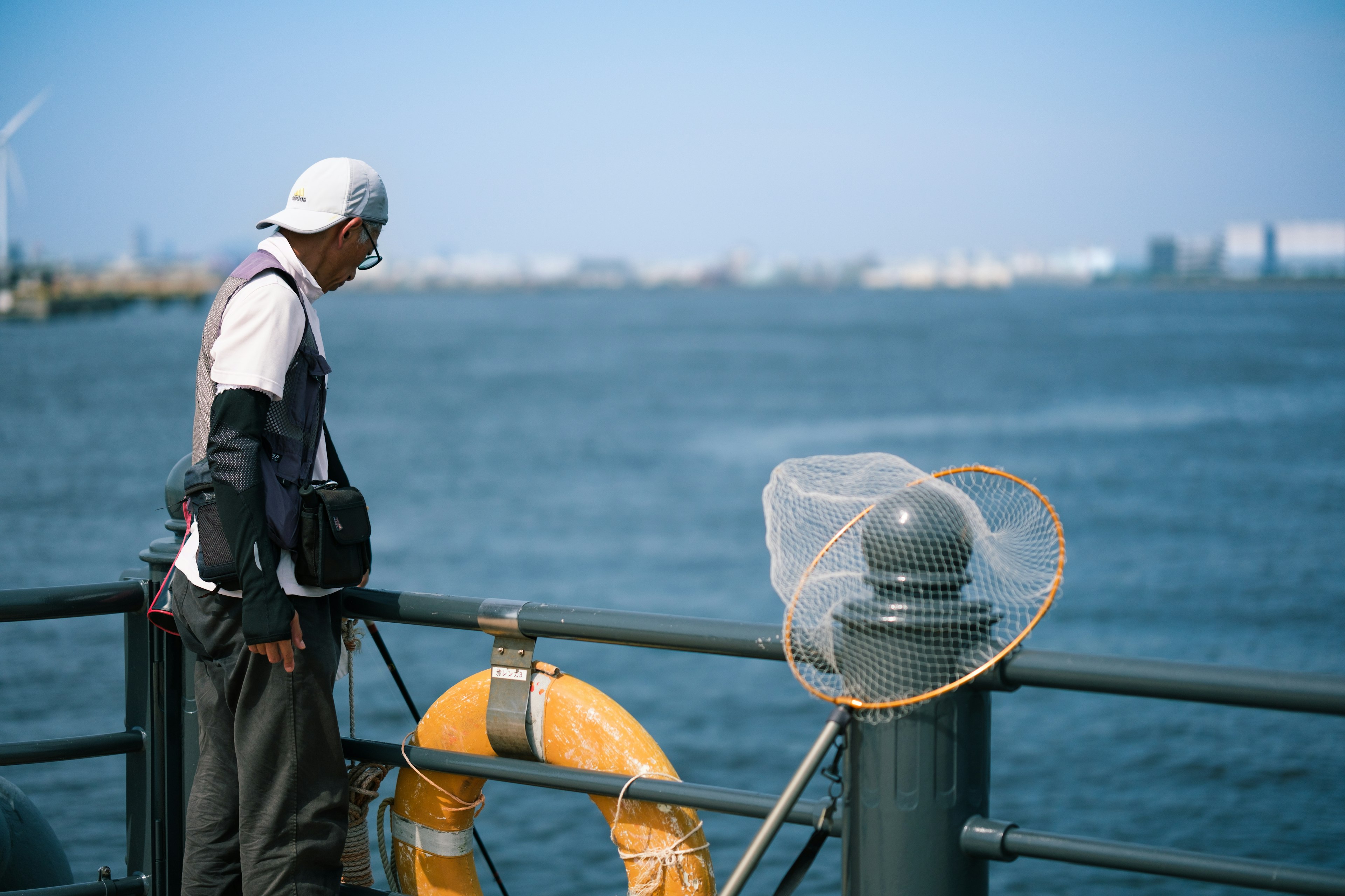 Mann schaut auf das Meer mit einem Rettungsring und einem Netz