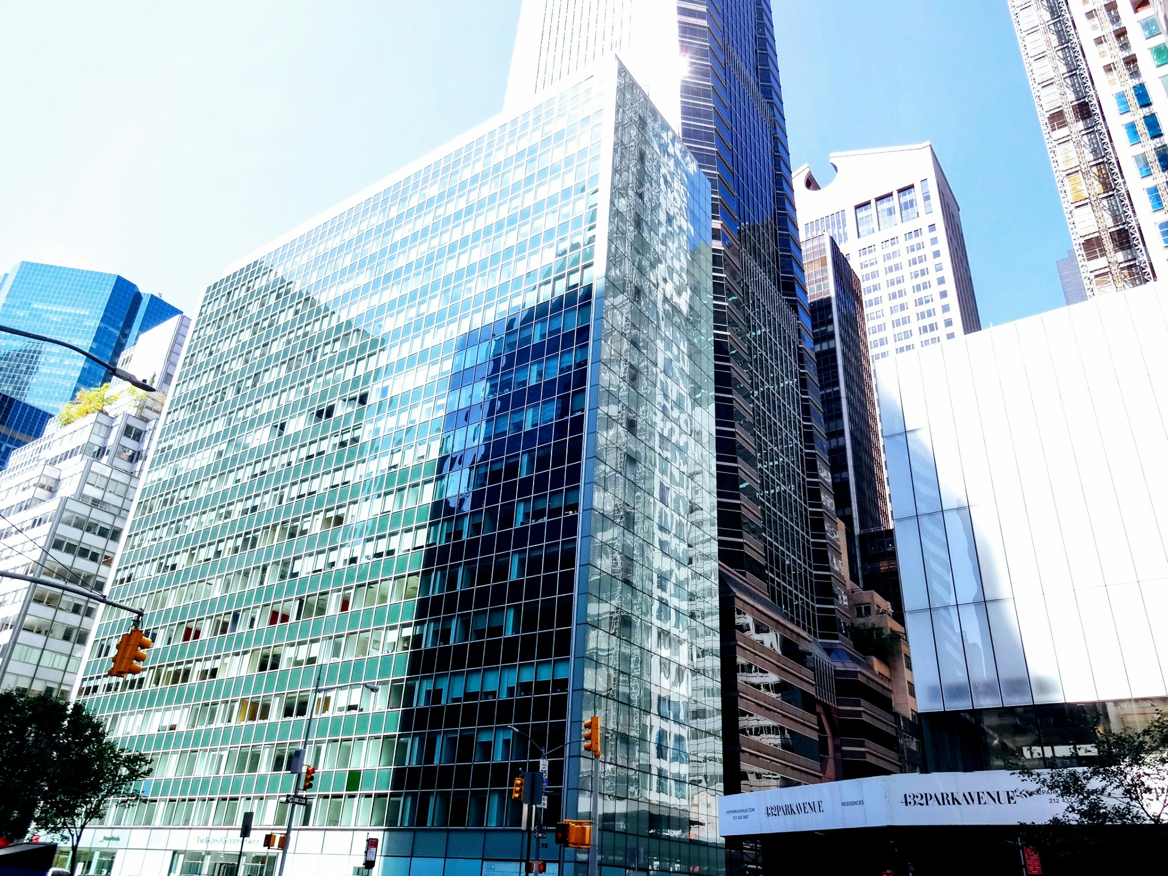 Modern skyscraper exterior with glass facade reflecting blue sky and neighboring buildings