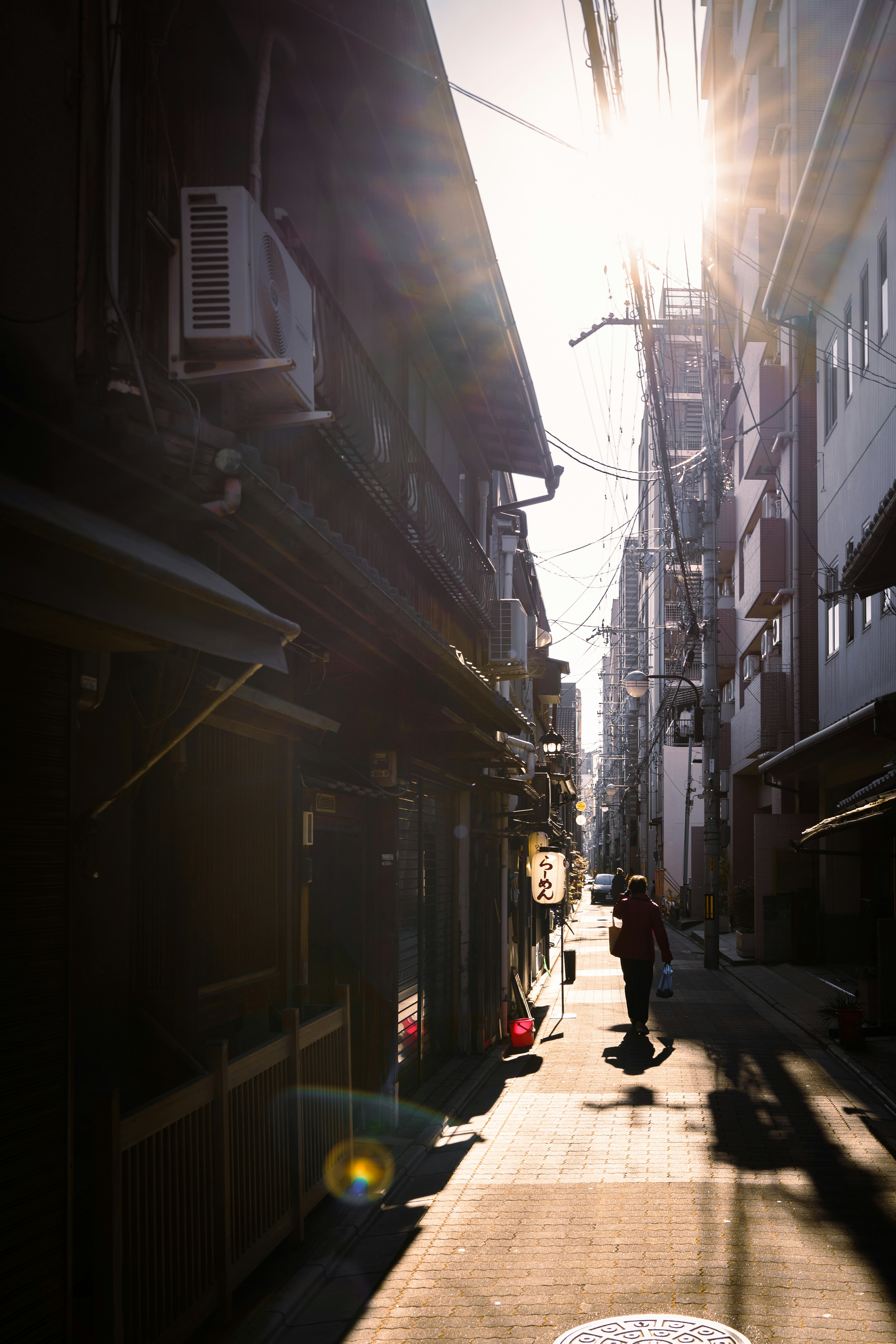 Narrow alley with a silhouetted person and sunlight