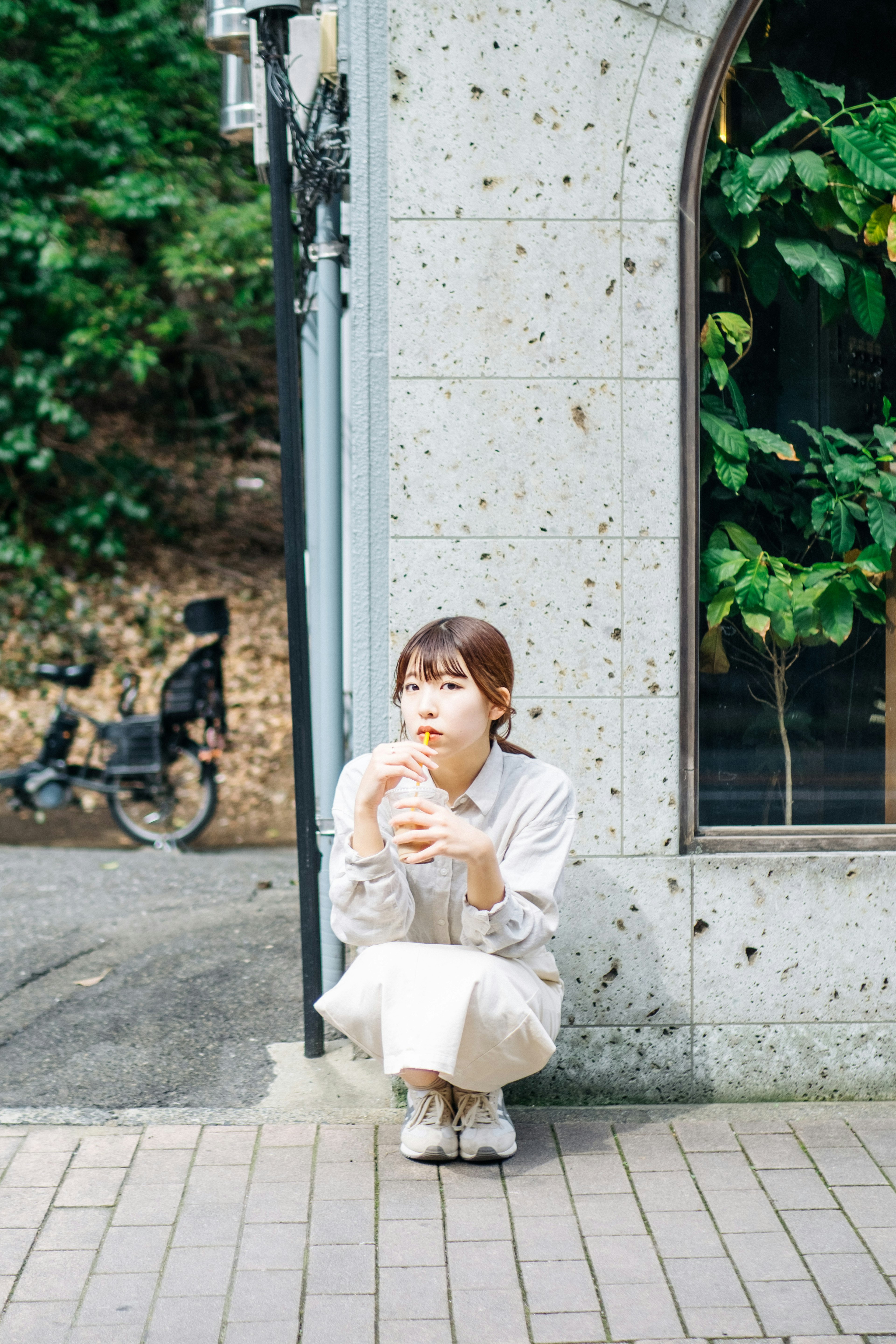 Woman sitting at a street corner holding a coffee cup