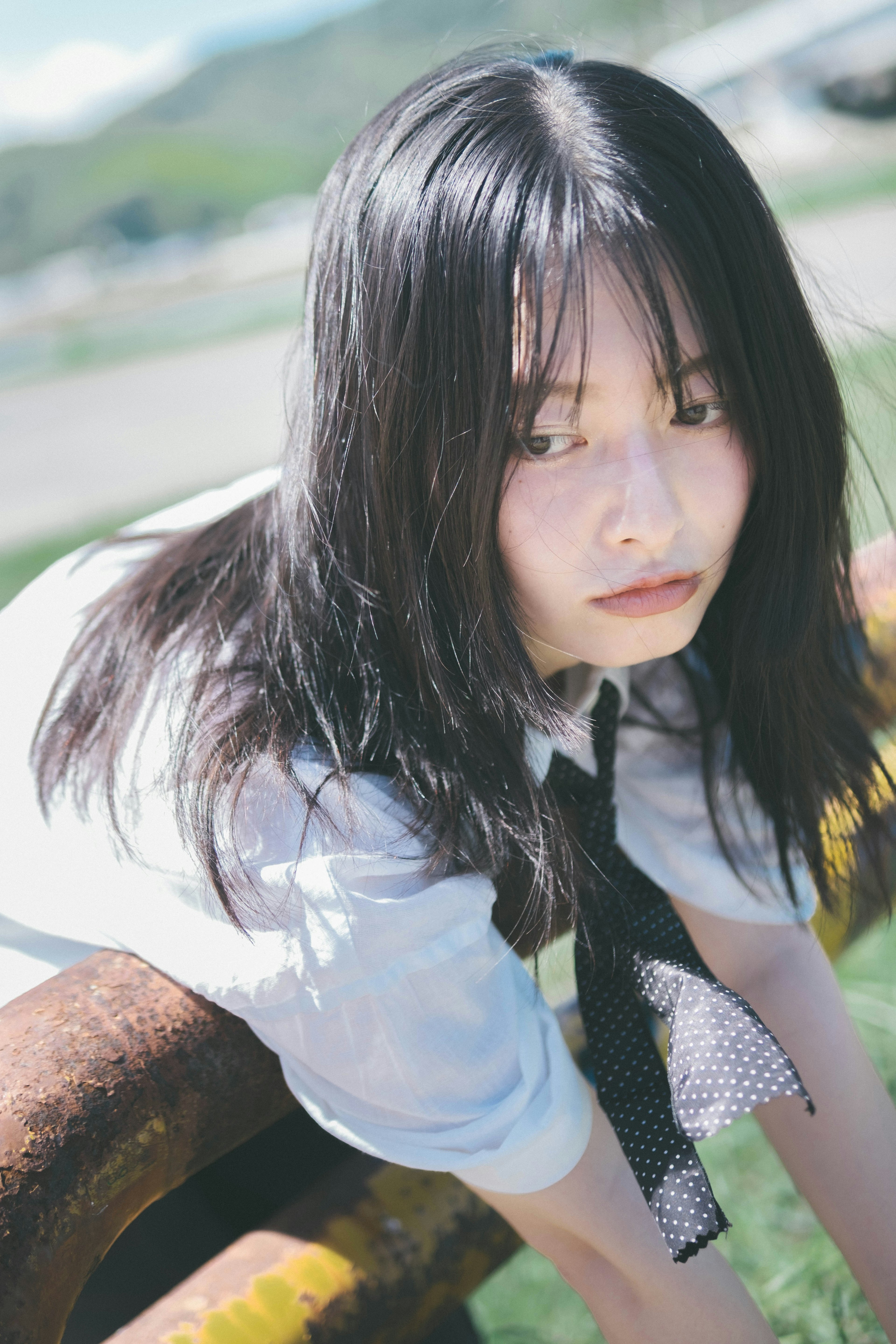 Portrait of a woman leaning on a metal pipe under a blue sky