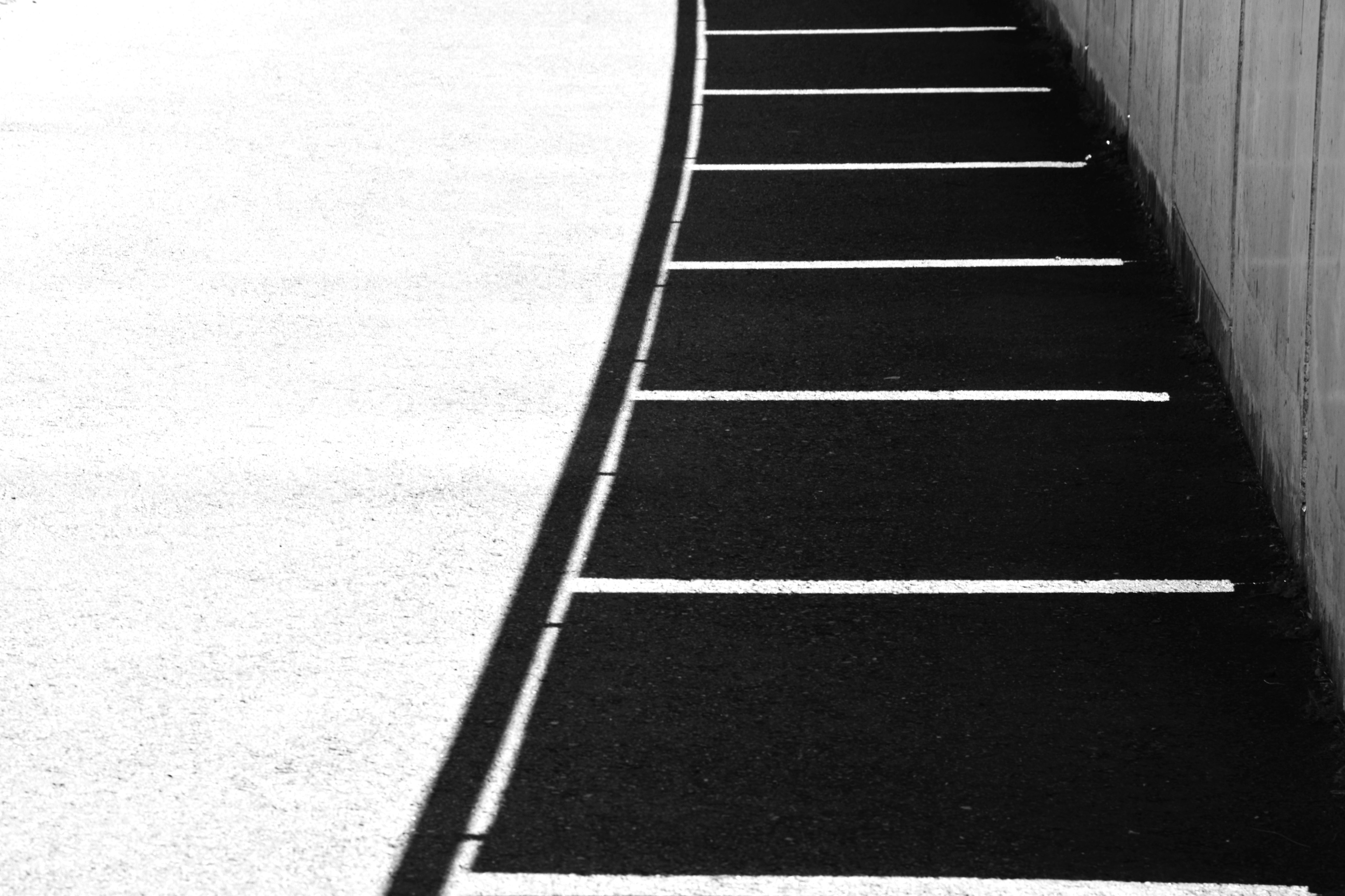 Curved parking spaces in black and white with part of a wall