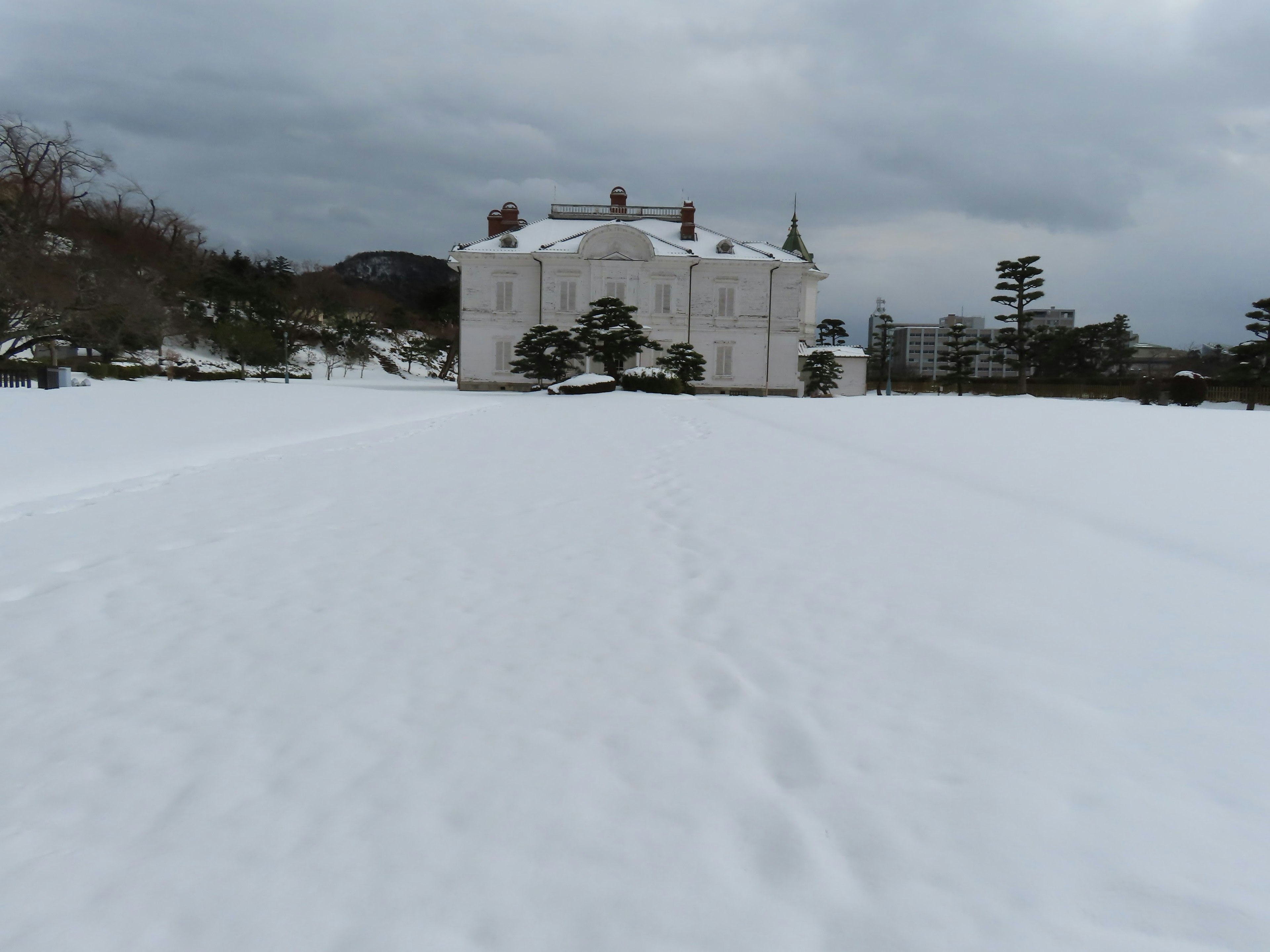 雪に覆われた広場に立つ白い建物と曇り空