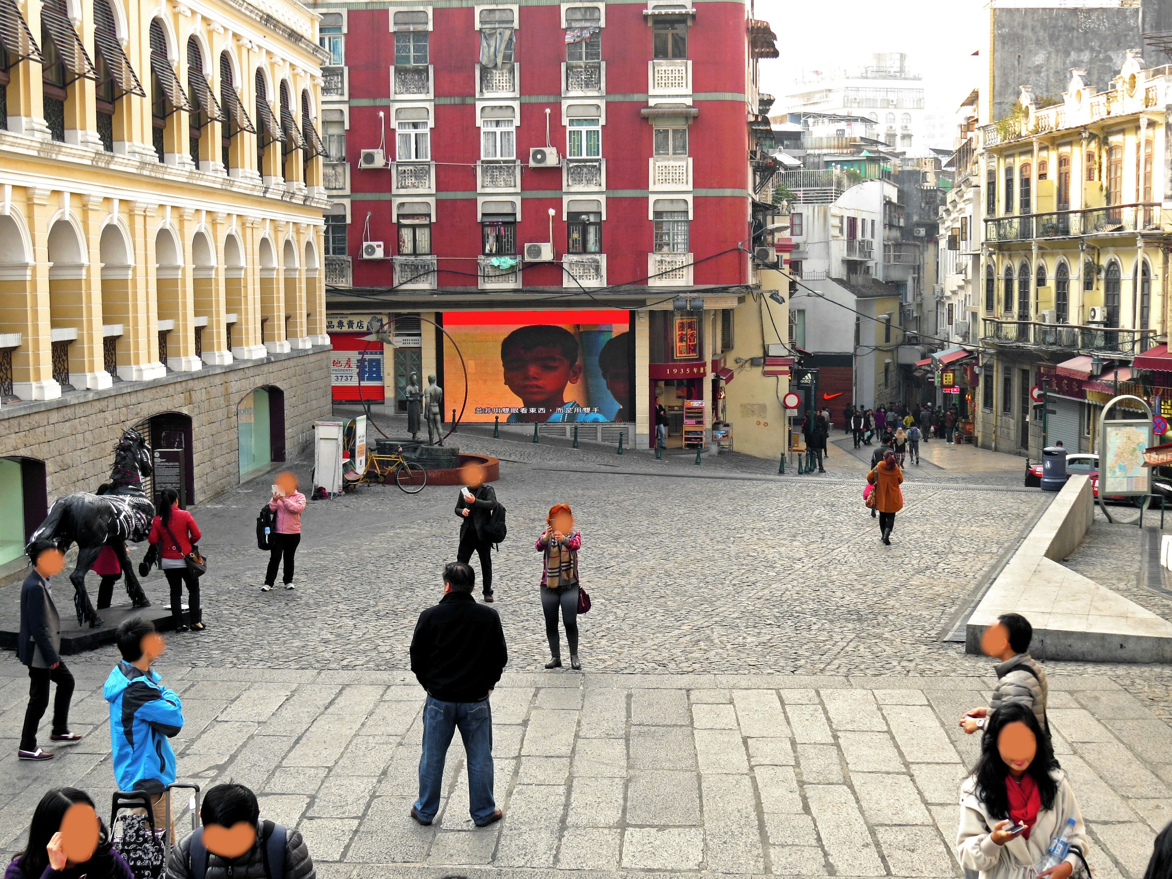 A cobblestone square filled with people and colorful buildings