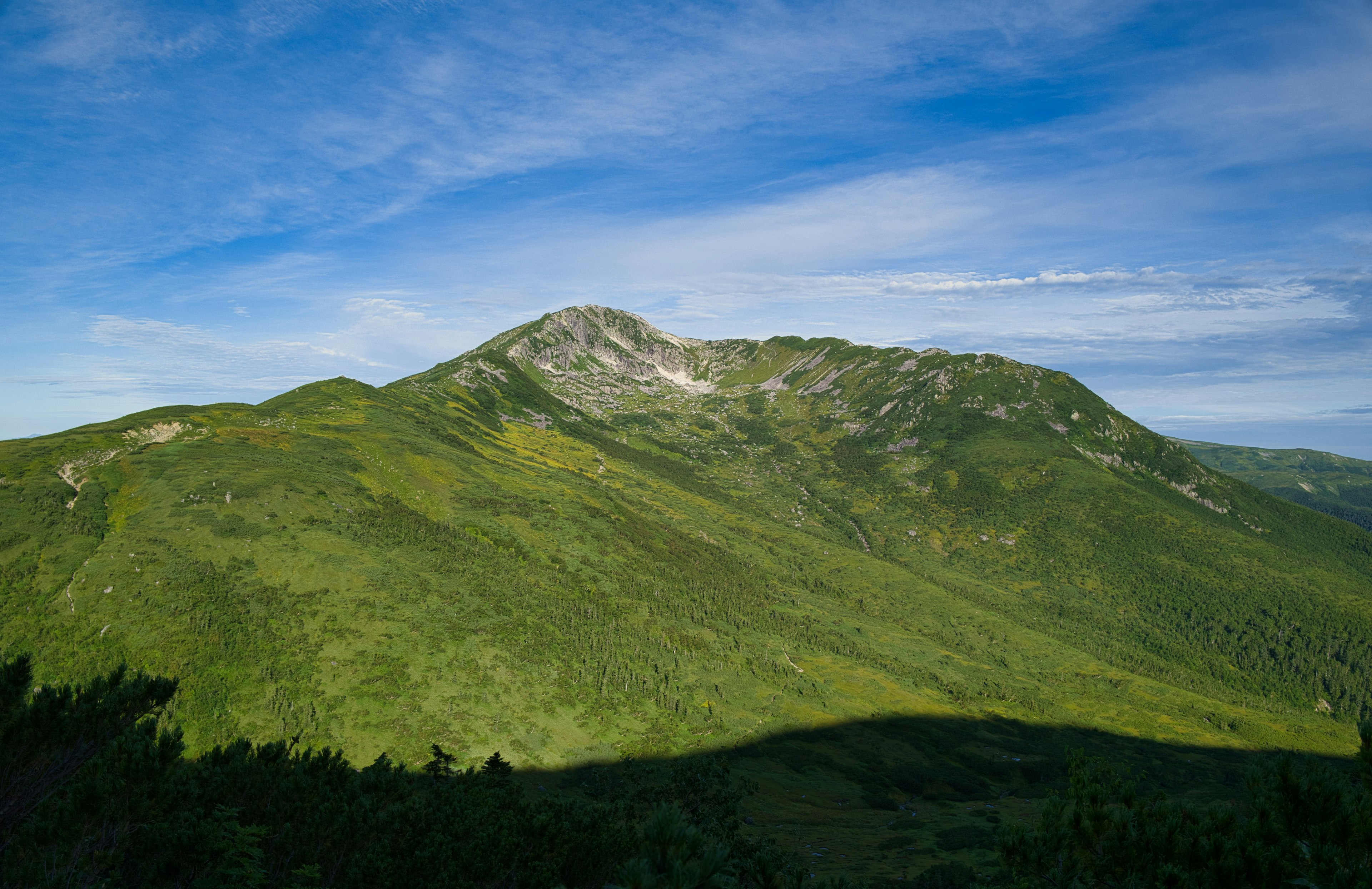 Üppige grüne Berglandschaft mit blauem Himmel