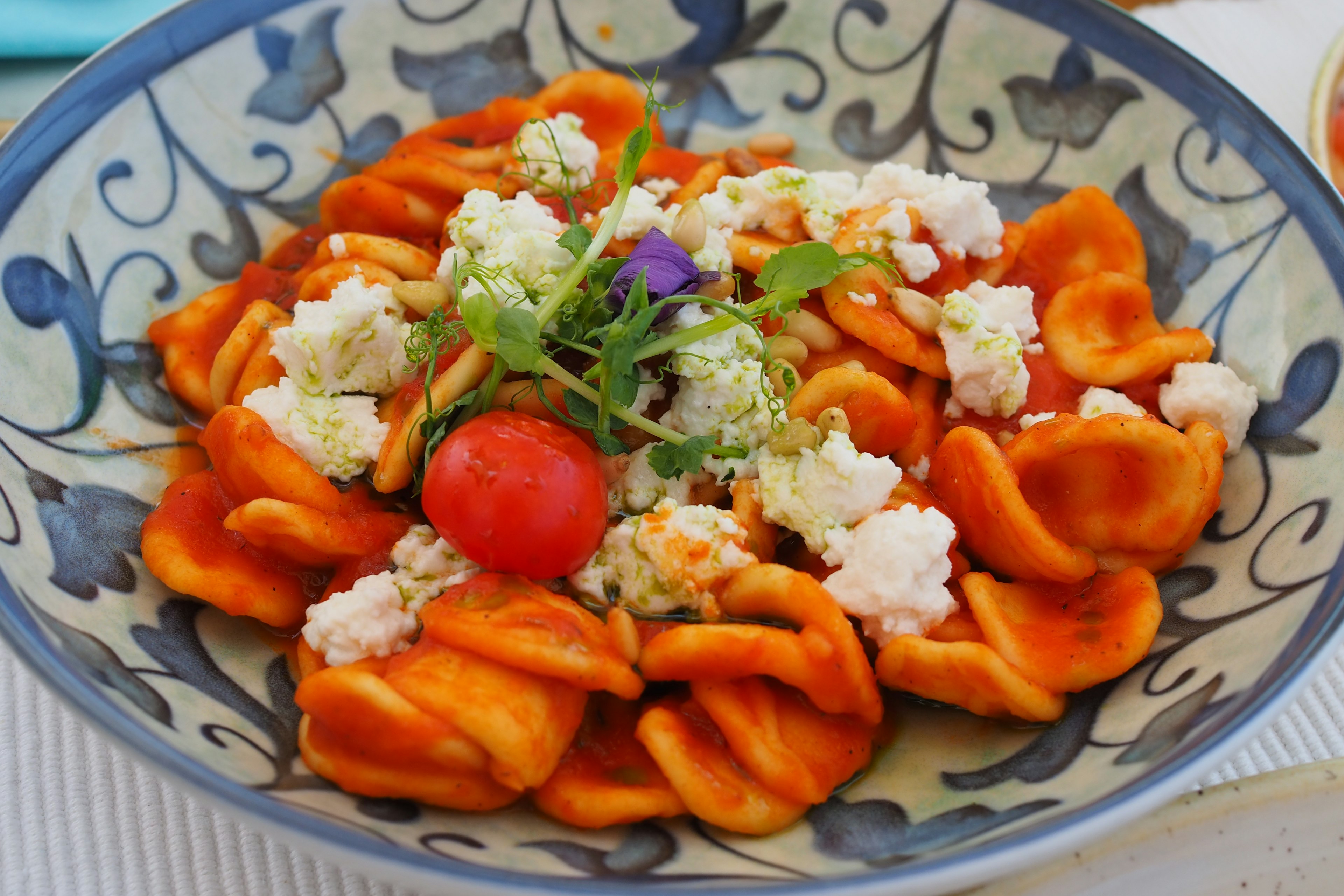 Plato de orecchiette con salsa naranja y ricotta acompañado de tomates cherry